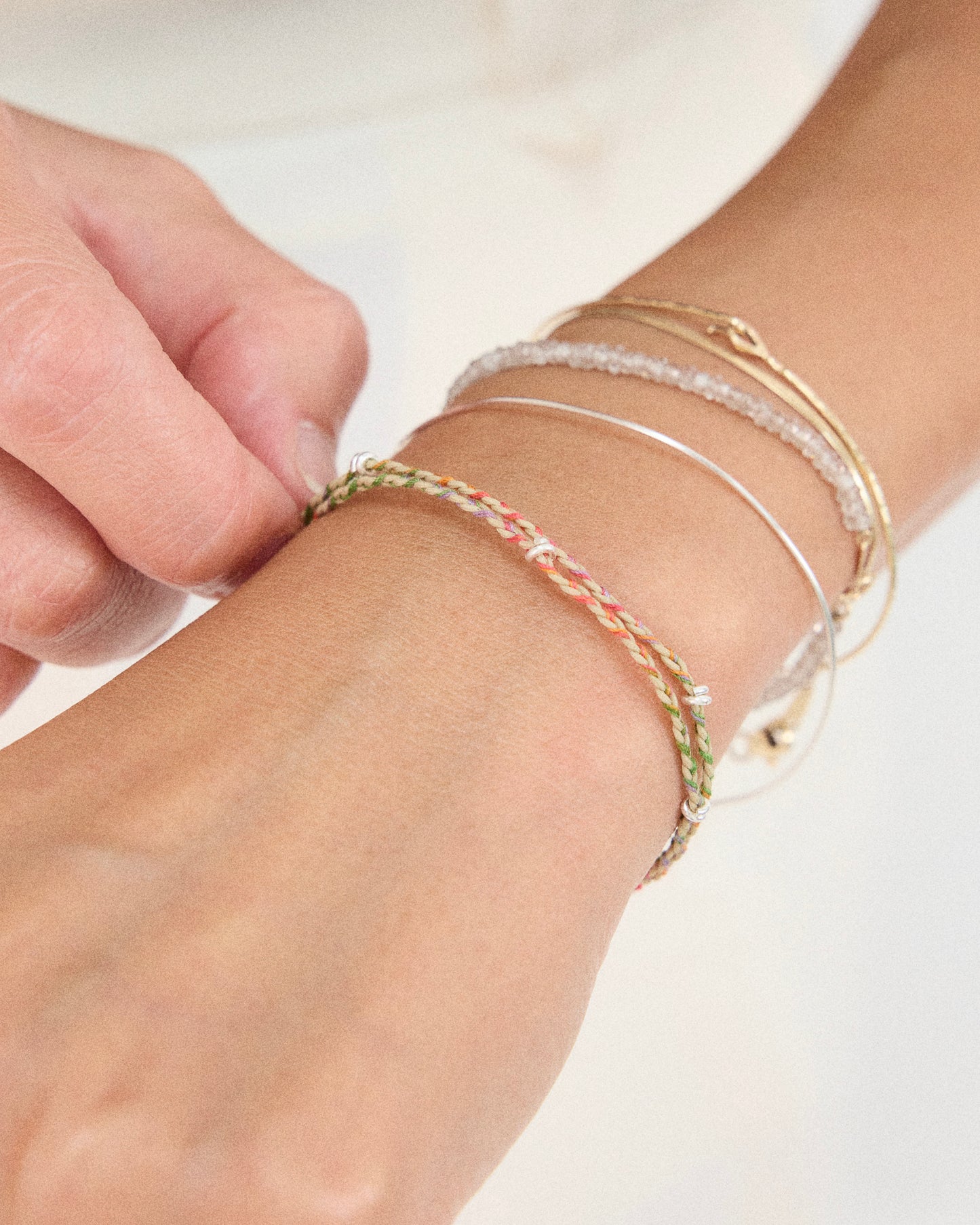 Delicate rainbow thread bracelet with sterling silver details styled on wrist