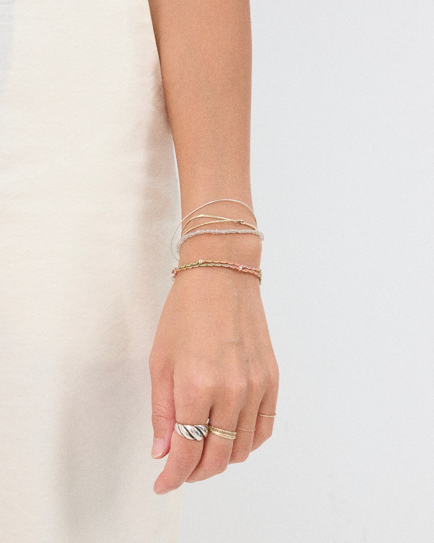 Handwoven colorful bracelet paired with minimalist silver jewelry and stacking bracelets
