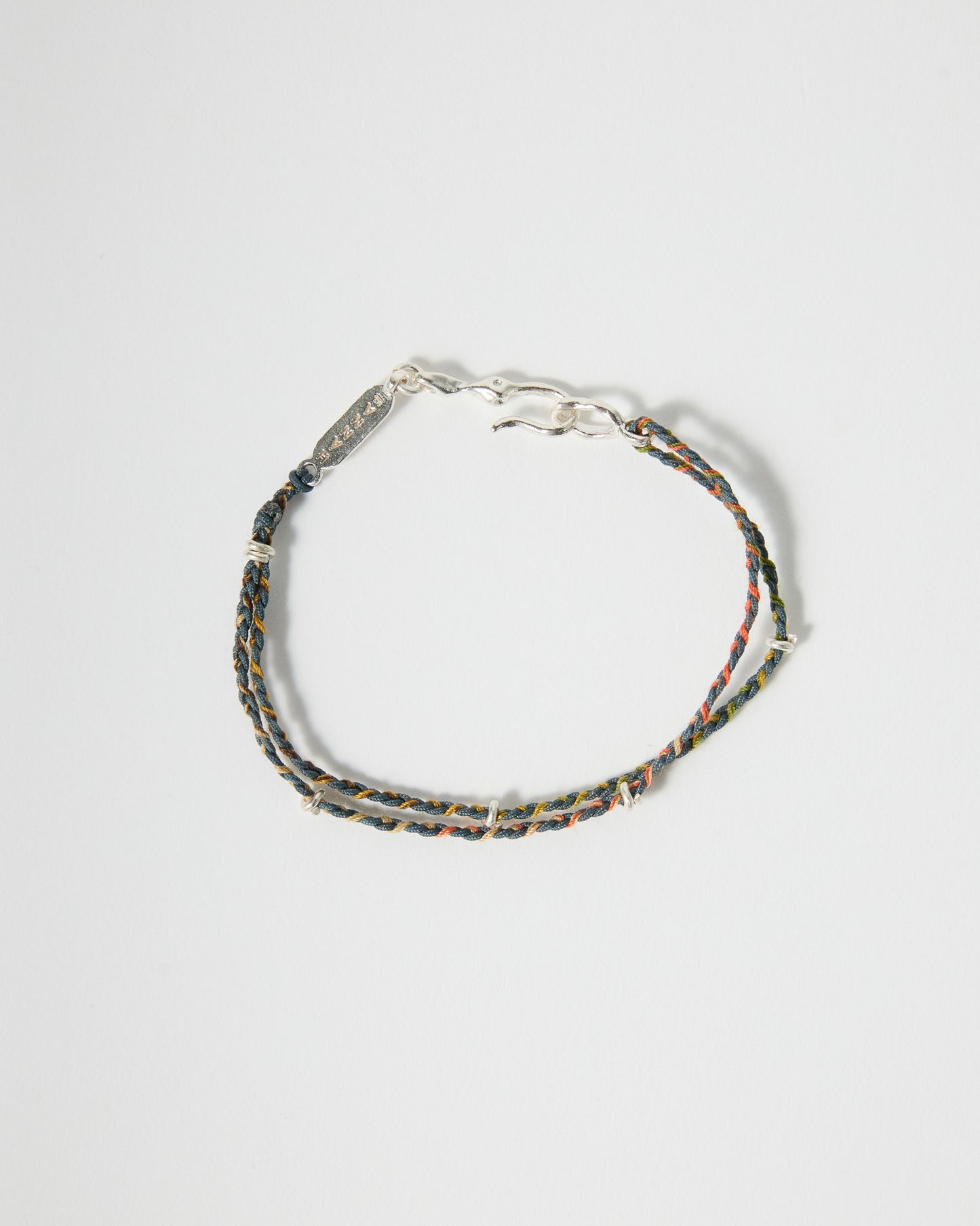 Handmade woven bracelet featuring blue, green, and warm earth-tone cords with sterling silver details