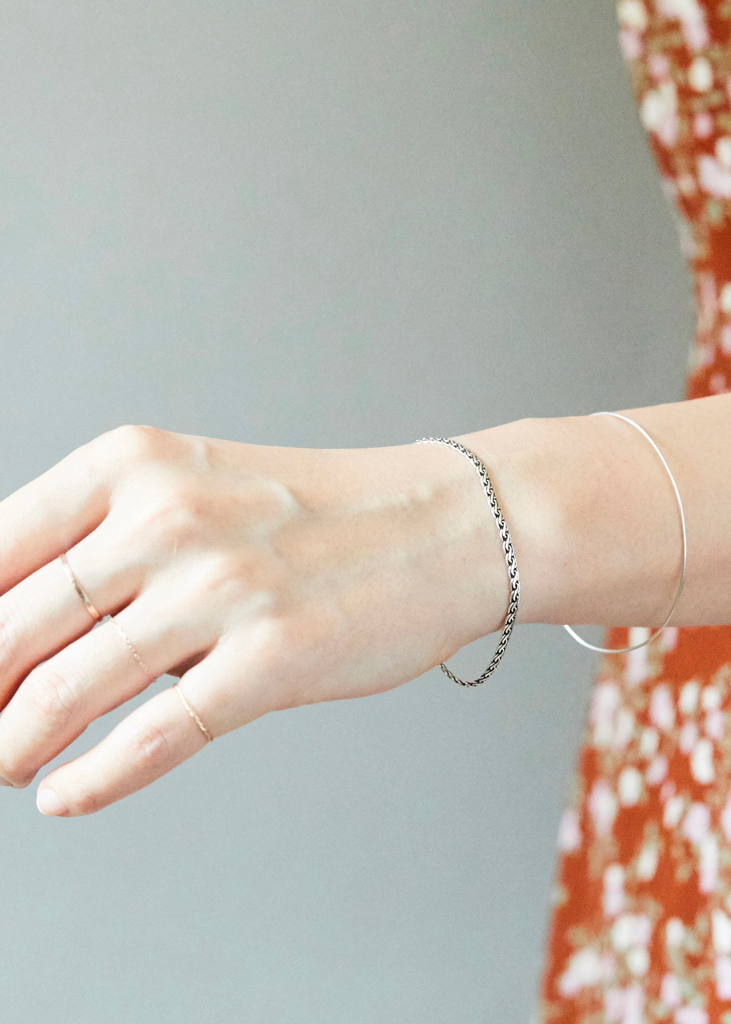 Sterling silver chain bracelet styled on wrist with layered bangles, featuring refined woven texture for an effortless everyday jewelry look.