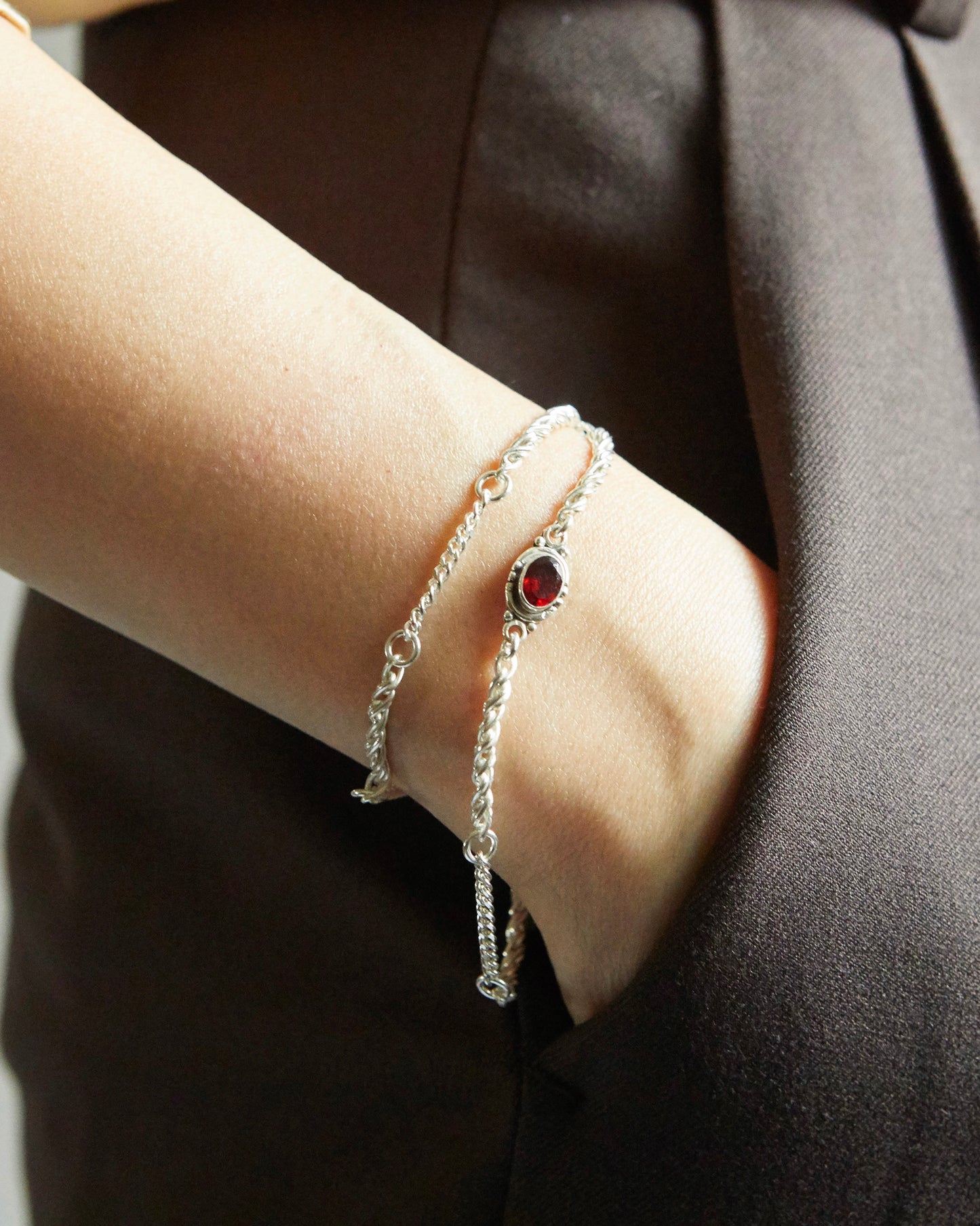 silver bracelet with red stone worn on wrist styled with neutral outfit