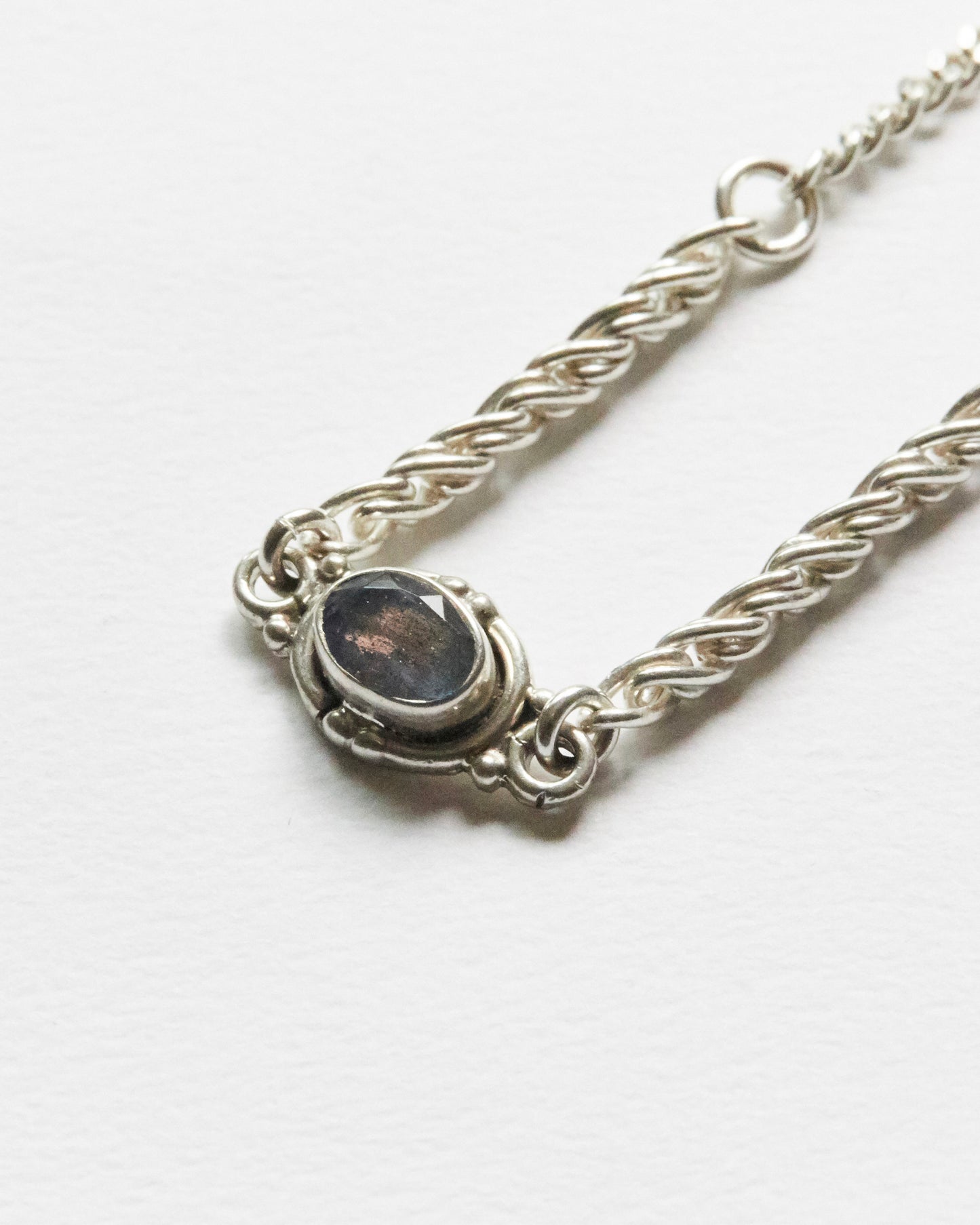 close-up of grey gemstone set in silver chain bracelet showing texture and detail