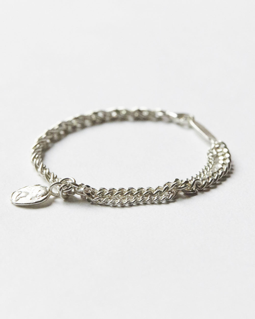 Hanna543 silver chain bracelet featuring contrasting twisted and curb chain links with an organic coin charm for a modern minimalist style.