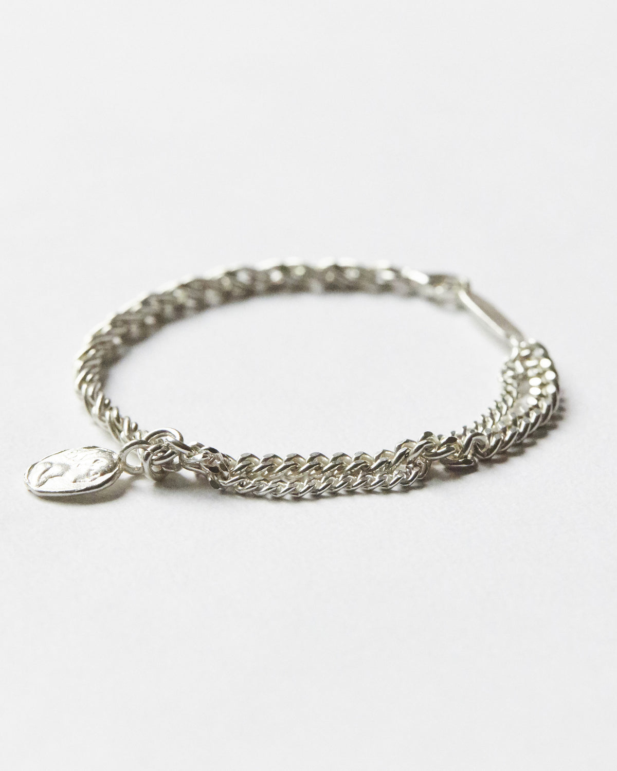 Hanna543 silver chain bracelet featuring contrasting twisted and curb chain links with an organic coin charm for a modern minimalist style.