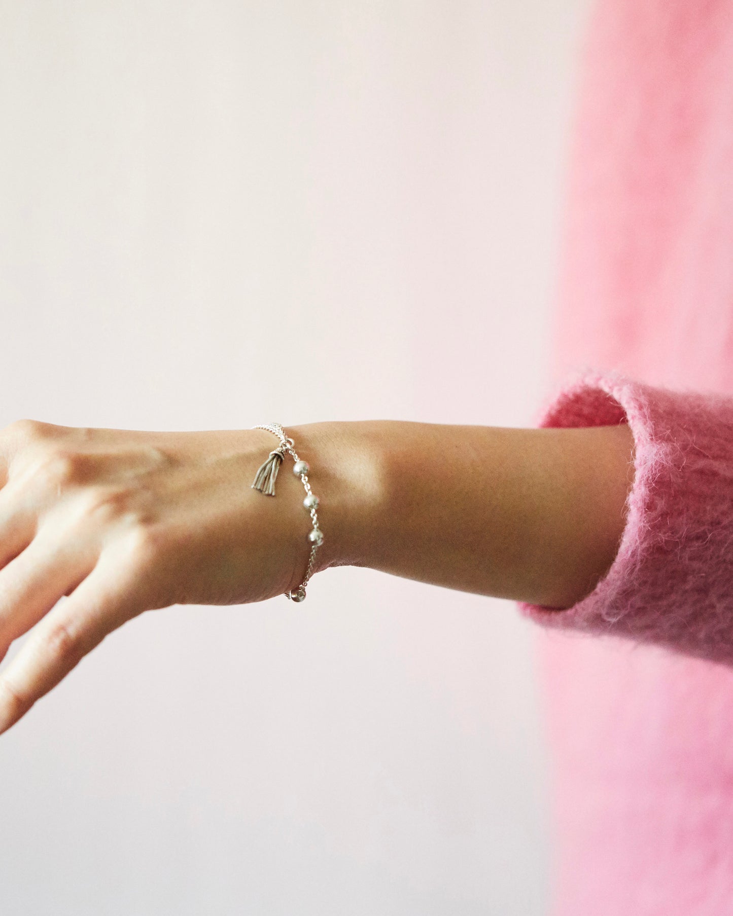 silver bead bracelet with tassel detail worn on wrist with pink knit outfit