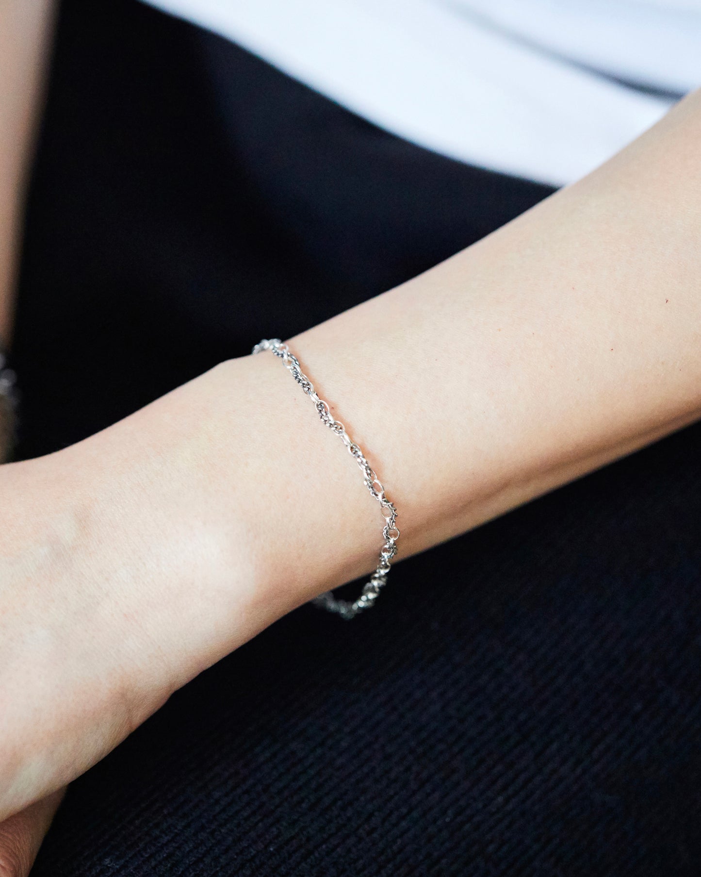 Textured sterling silver mixed chain bracelet worn close-up on wrist