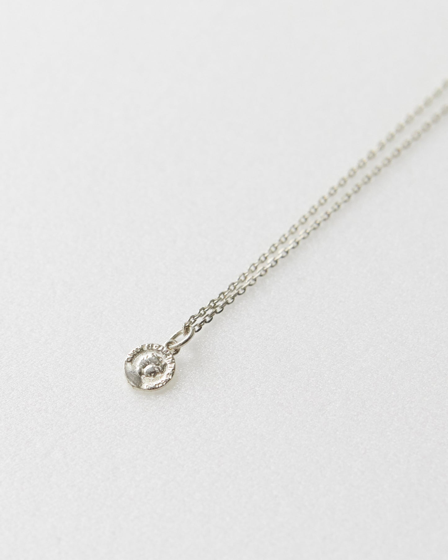 Antique-style coin necklace with portrait engraving, photographed from front