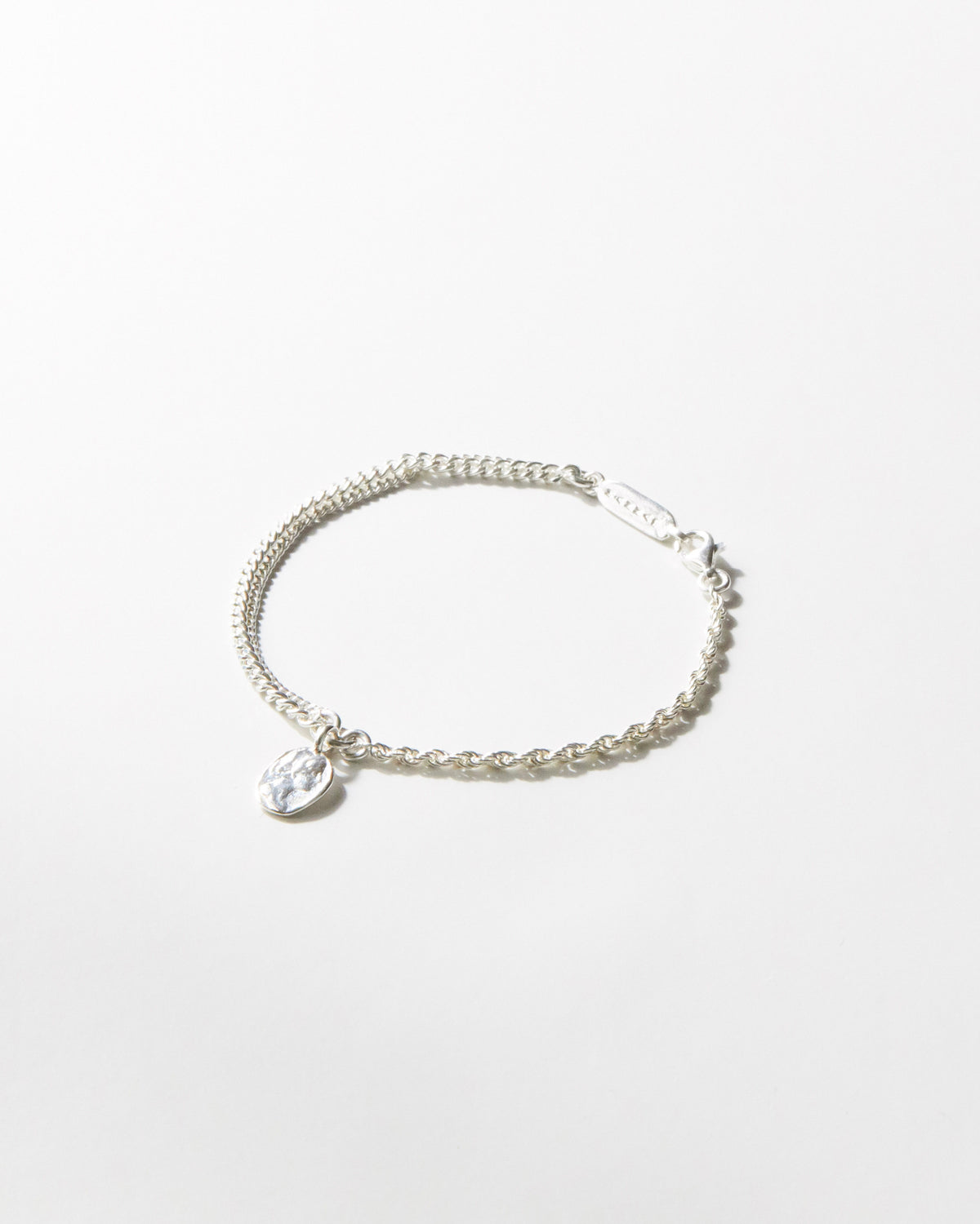 Flat lay of B507 925 silver bracelet with hammered medallion pendant, white background
