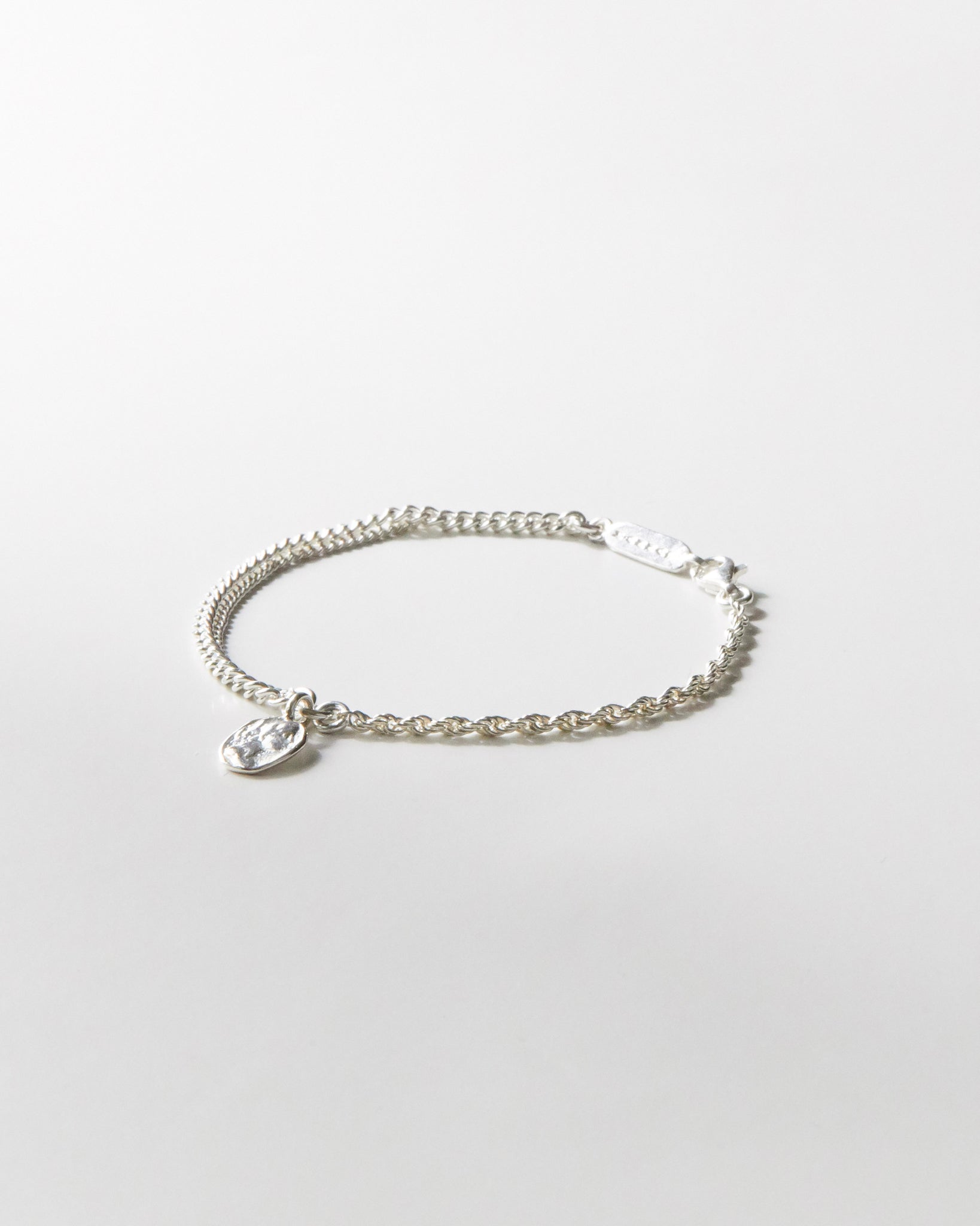 925 silver bracelet with dual chain detail and textured coin pendant on white background