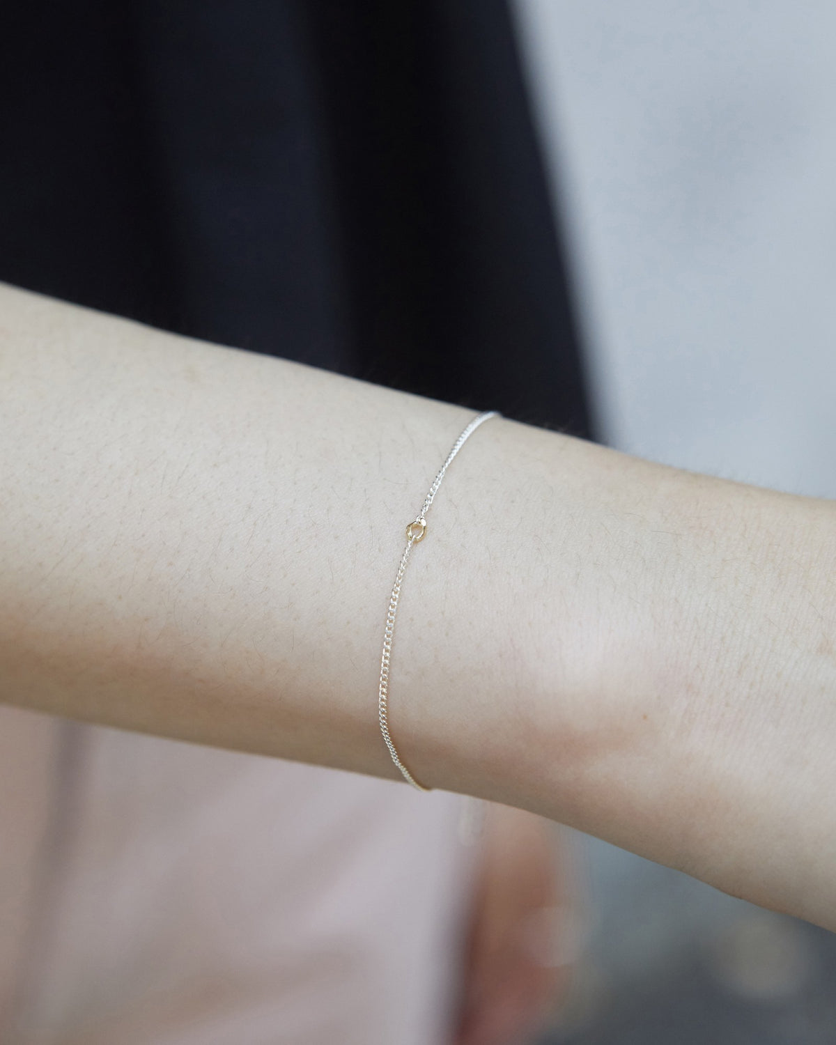 Wrist wearing a thin silver chain bracelet with a tiny gold accent – HANNA543 B535 gold note chain