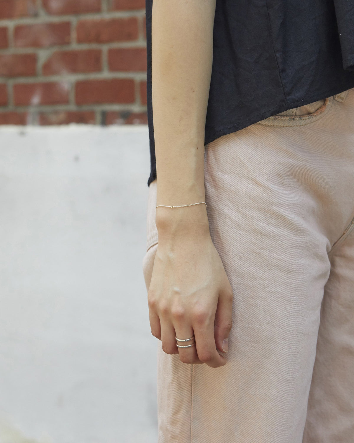 Silver chain bracelet with a gold accent worn with a black top and pink trousers – HANNA543 B535 gold note chain