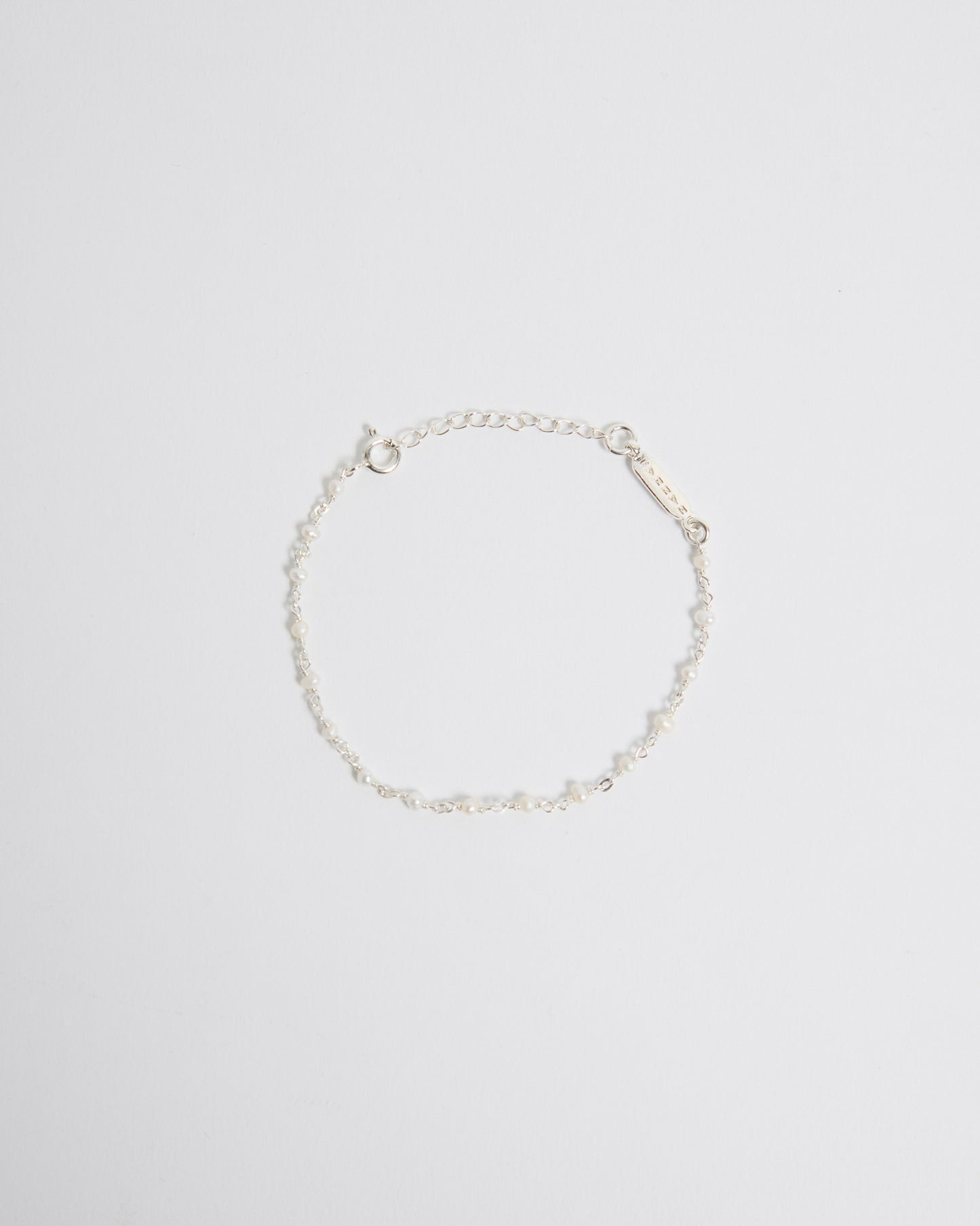Top view of delicate sterling silver bracelet with tiny pearl details