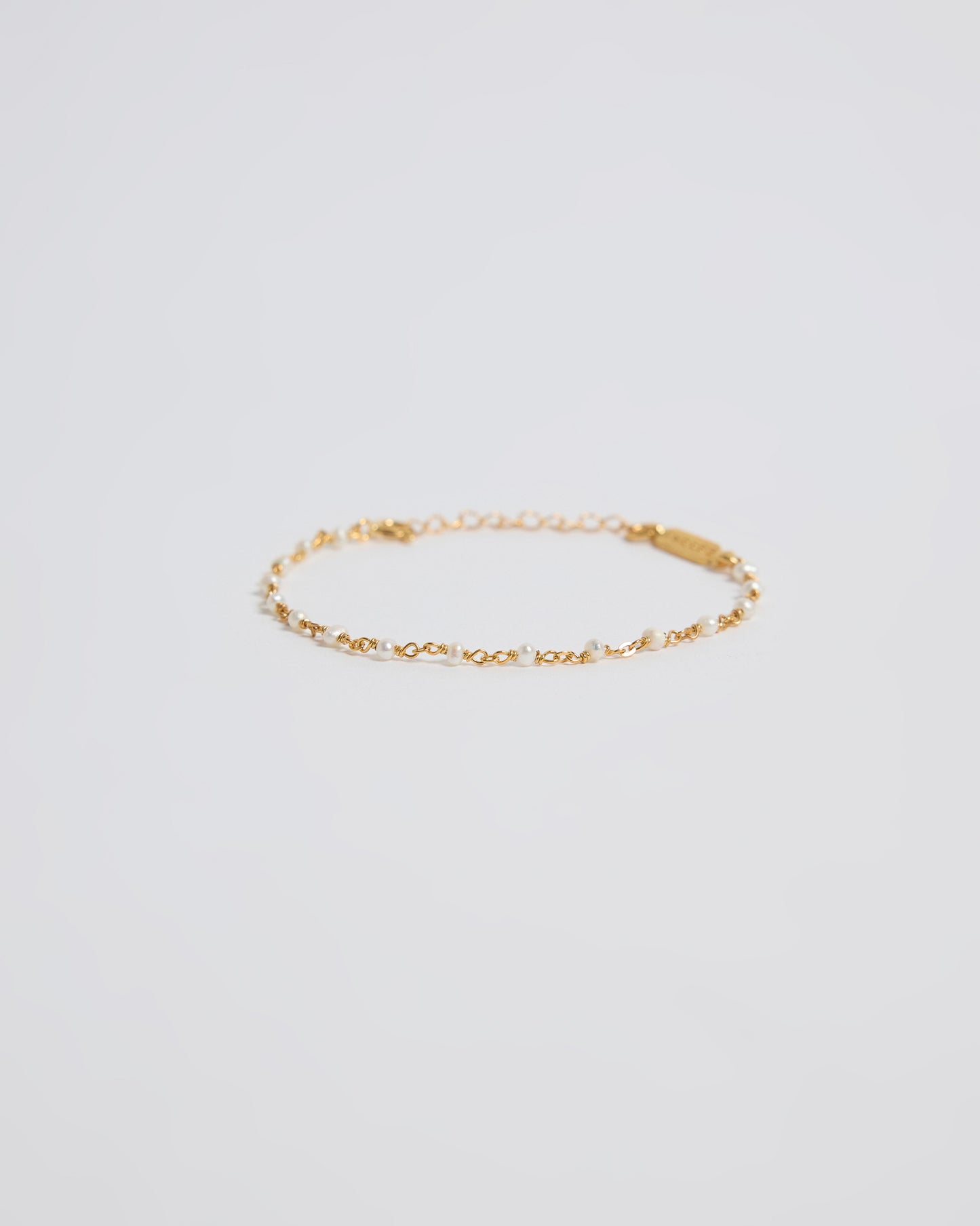 Minimal gold pearl bracelet on clean white background