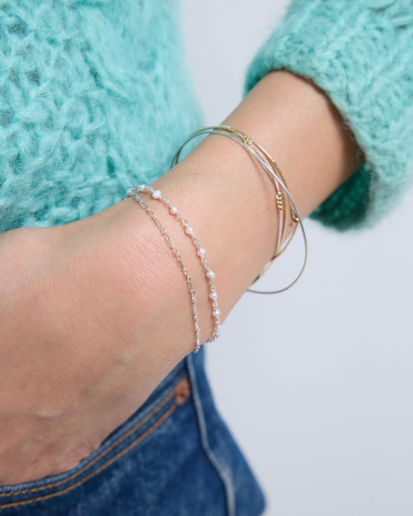 Close-up detail of silver layered pearl bracelet featuring tiny pearls and delicate chain texture