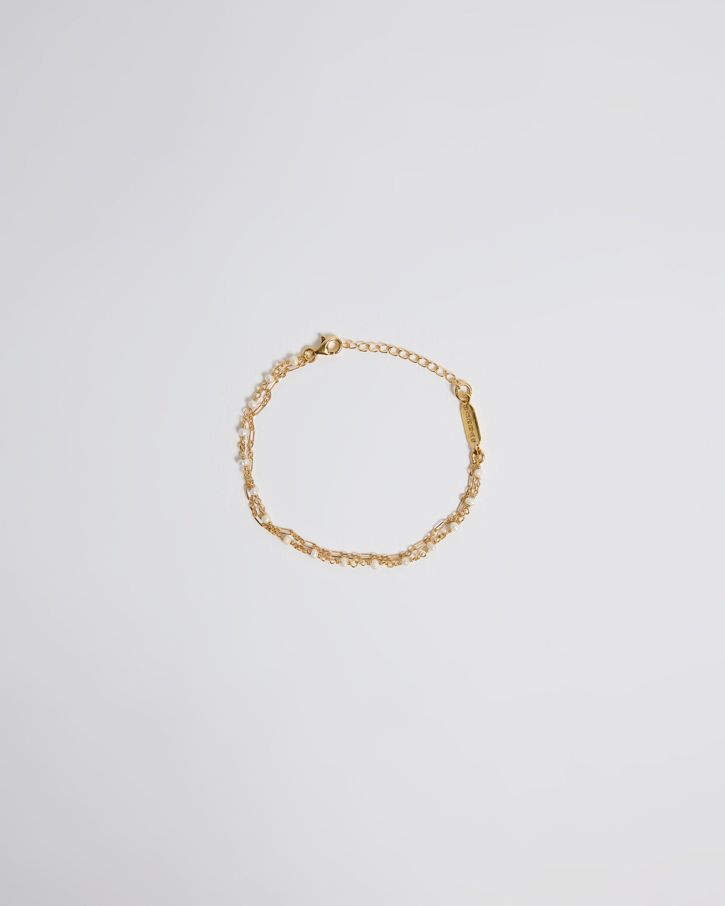 Top view of delicate gold pearl bracelet with double chain detail and adjustable clasp
