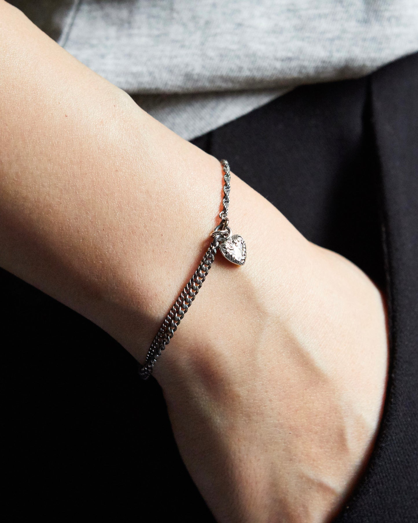 Close-up of a wrist wearing a bracelet with a heart-shaped charm.