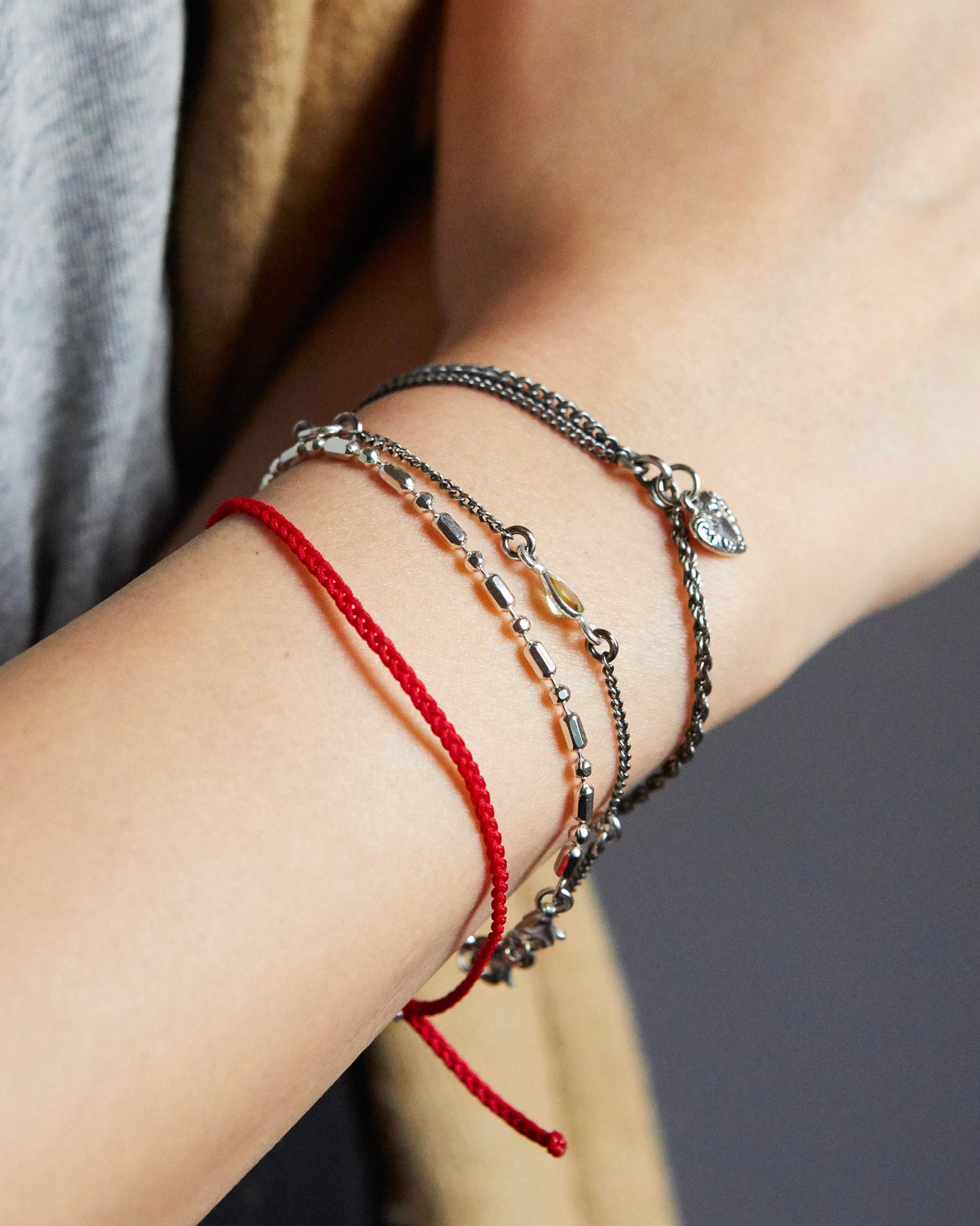 Silver heart charm bracelet styled with blue and silver thread bracelets for a casual look