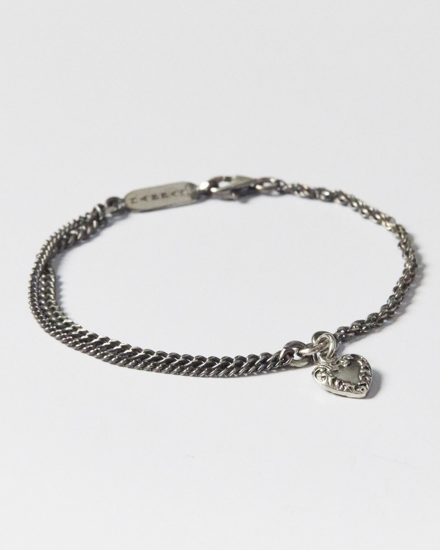 925 silver bracelet with double chain and vintage-style heart charm on white background