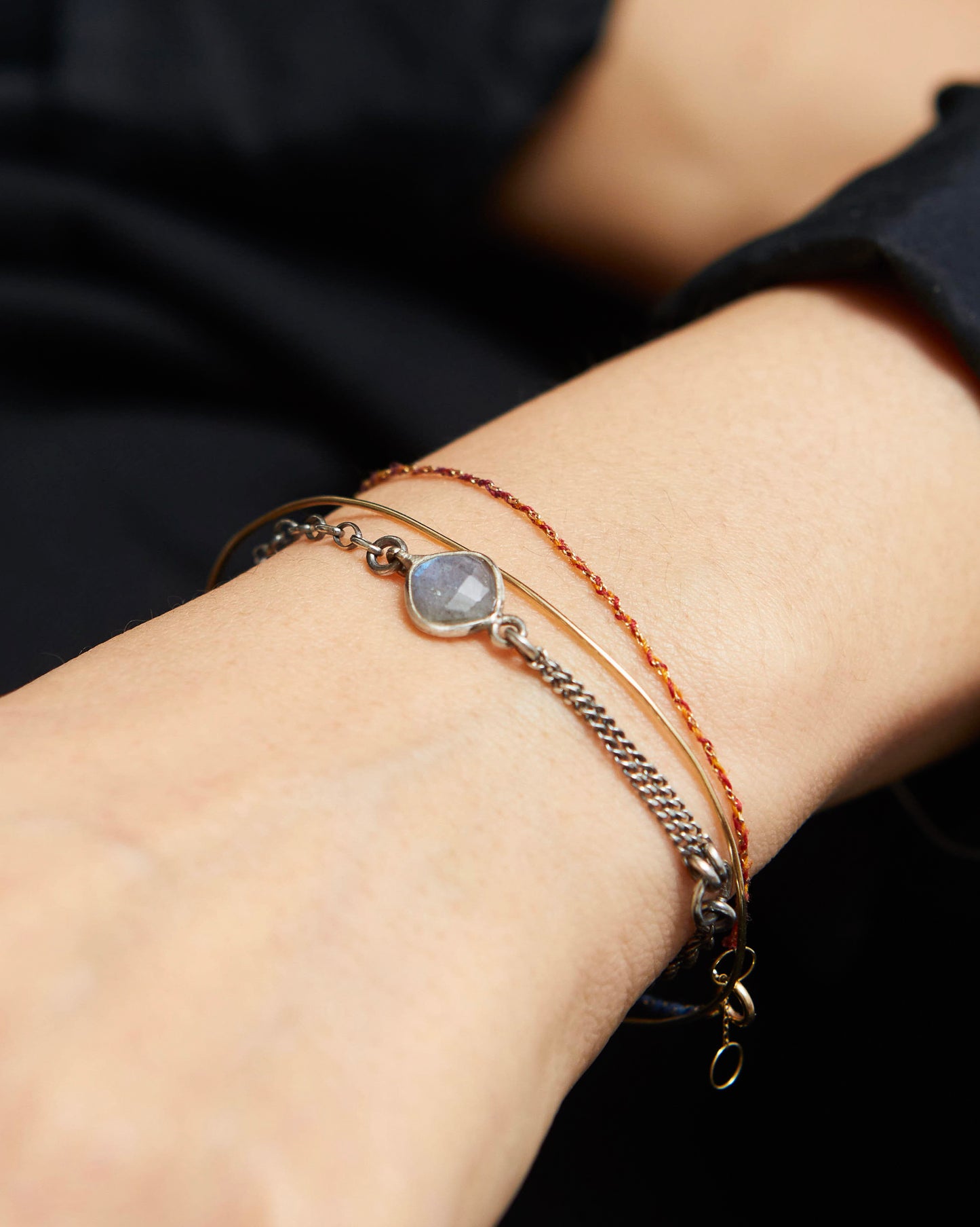 Close-up of a wrist wearing multiple bracelets with a dark background