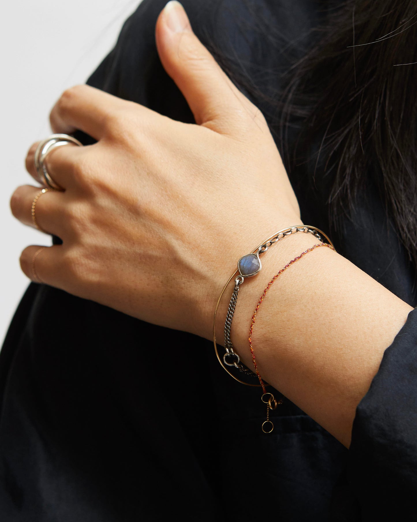 Hand wearing multiple bracelets on a plain background