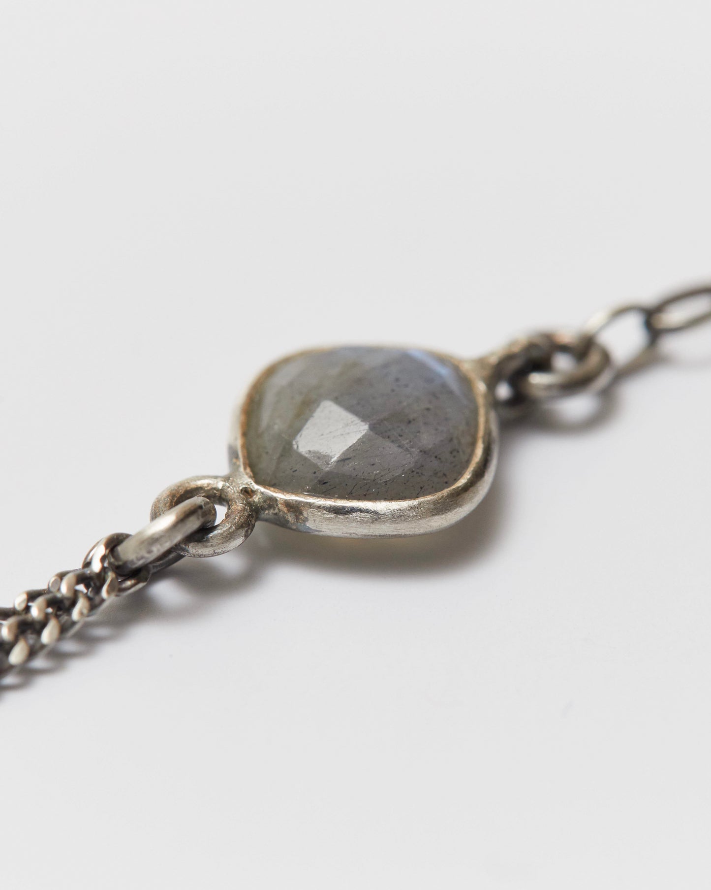 Silver bracelet with a labradorite stone on a light gray background
