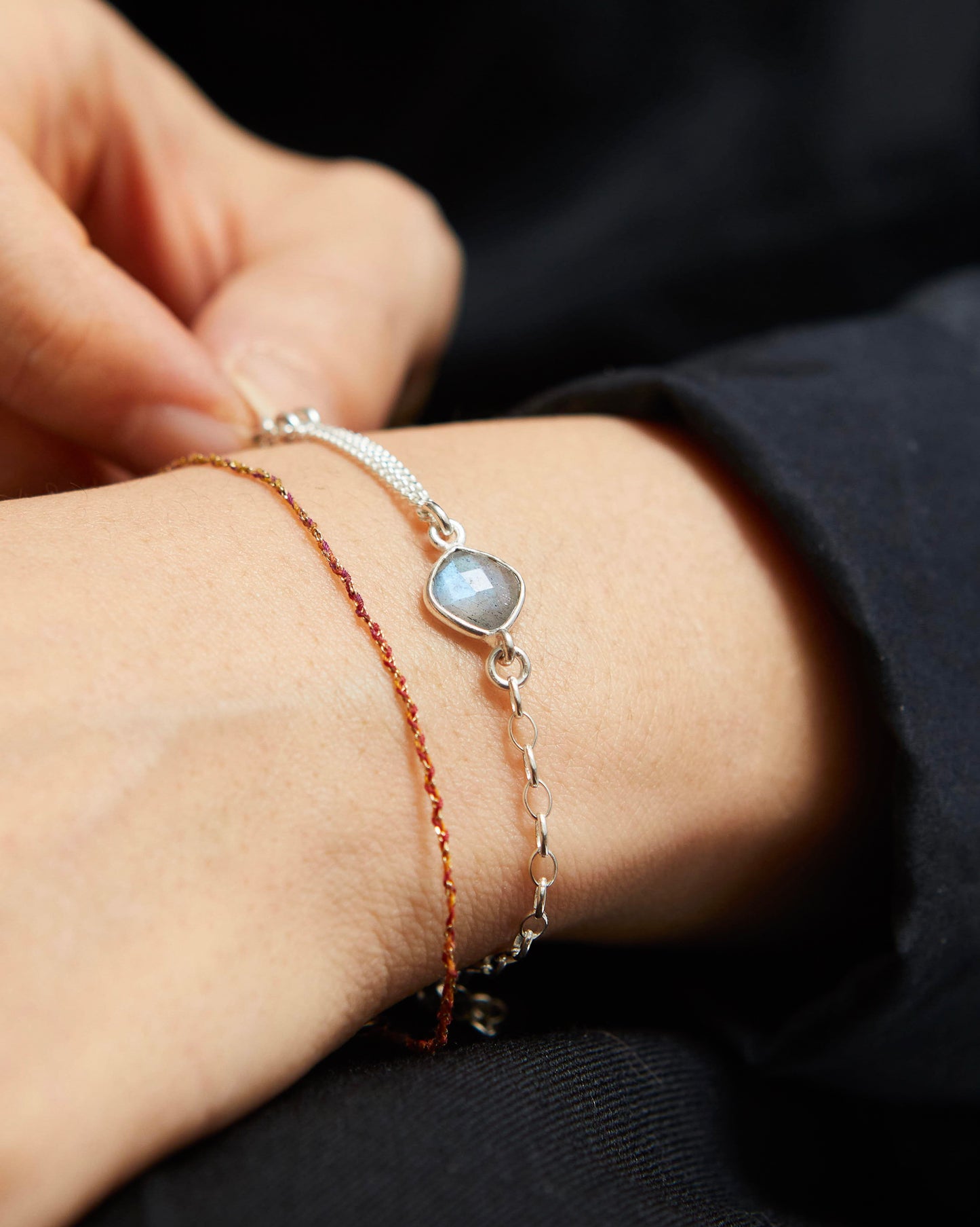 Close-up of a person's wrist wearing two bracelets with a dark background