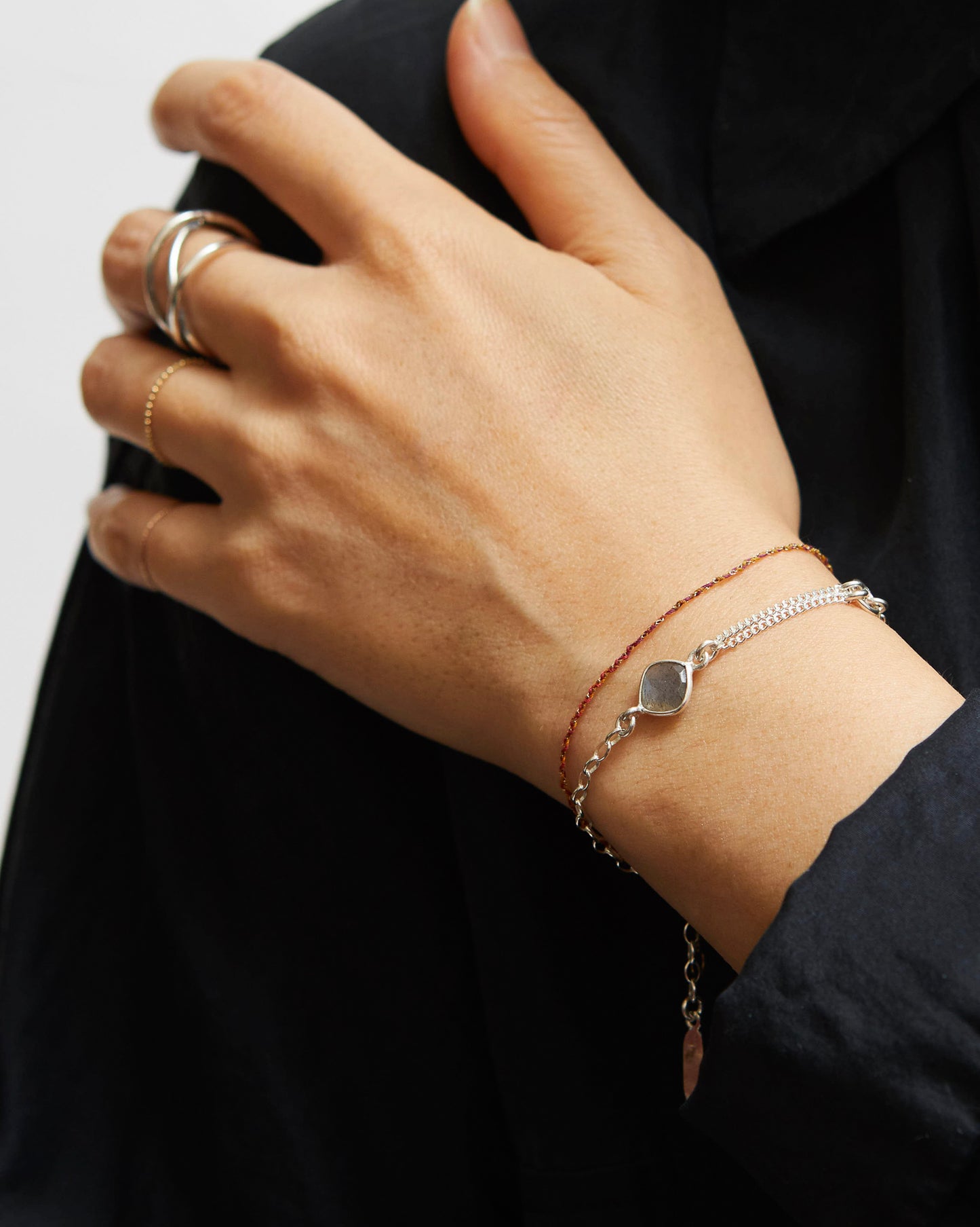 Hand wearing a silver bracelet with a black background