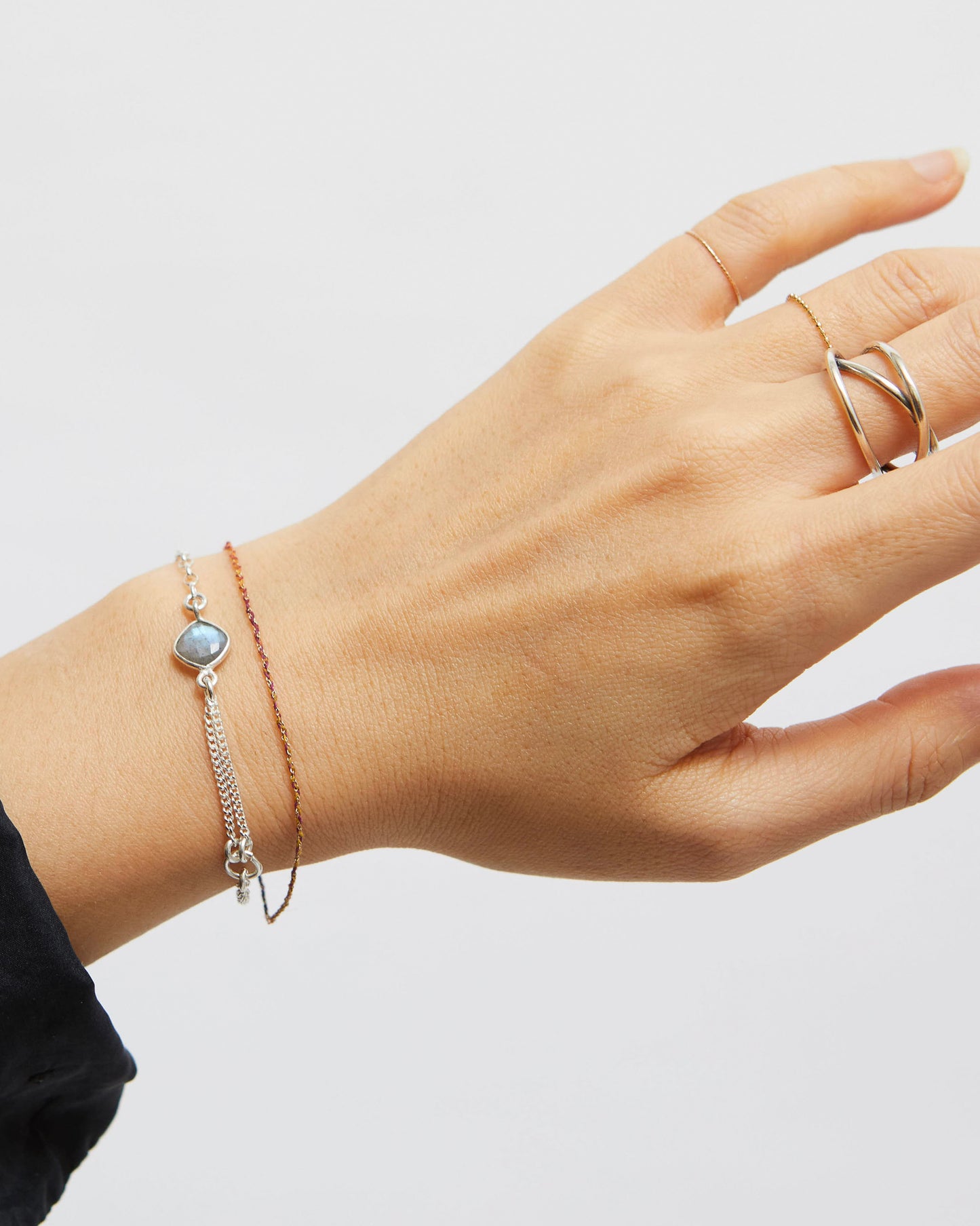Hand wearing a bracelet and ring on a plain background