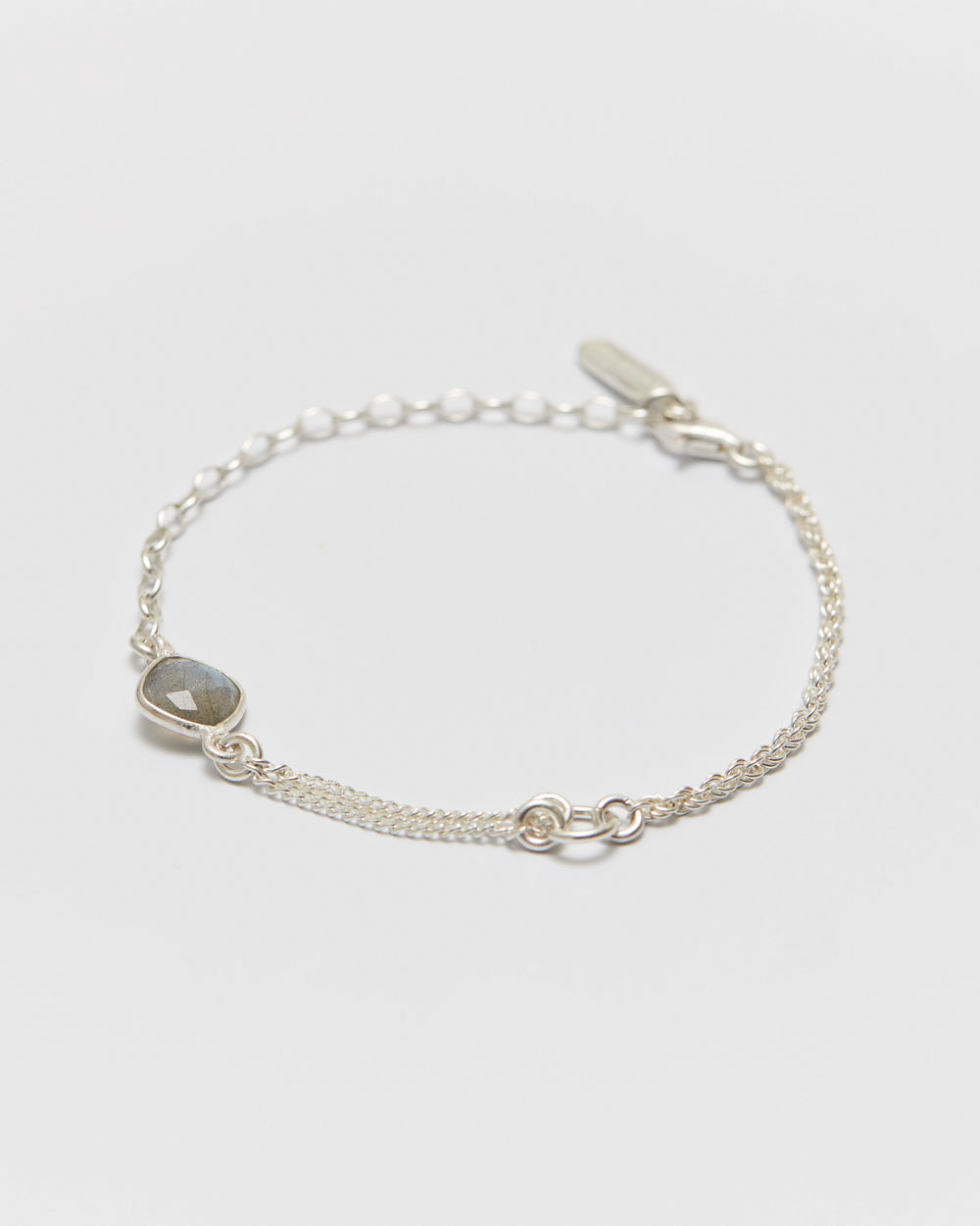 Silver bracelet with a small gemstone on a light gray background
