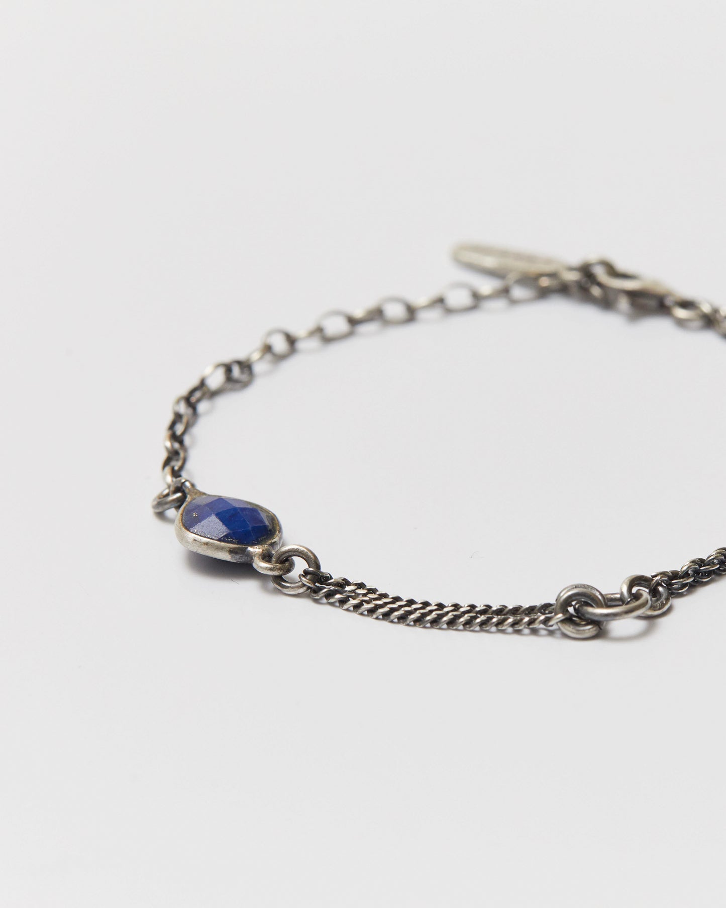 Silver bracelet with a blue gemstone on a white background