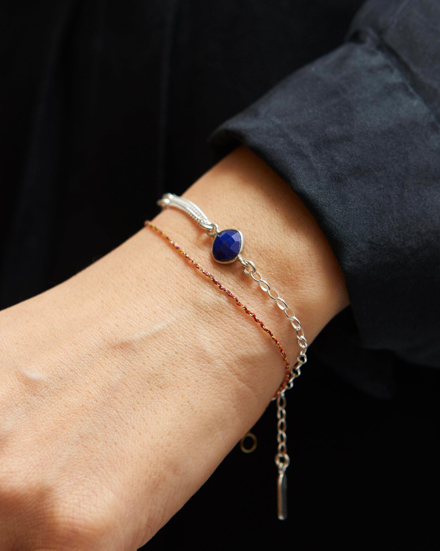 Close-up of a wrist wearing multiple bracelets with a dark background