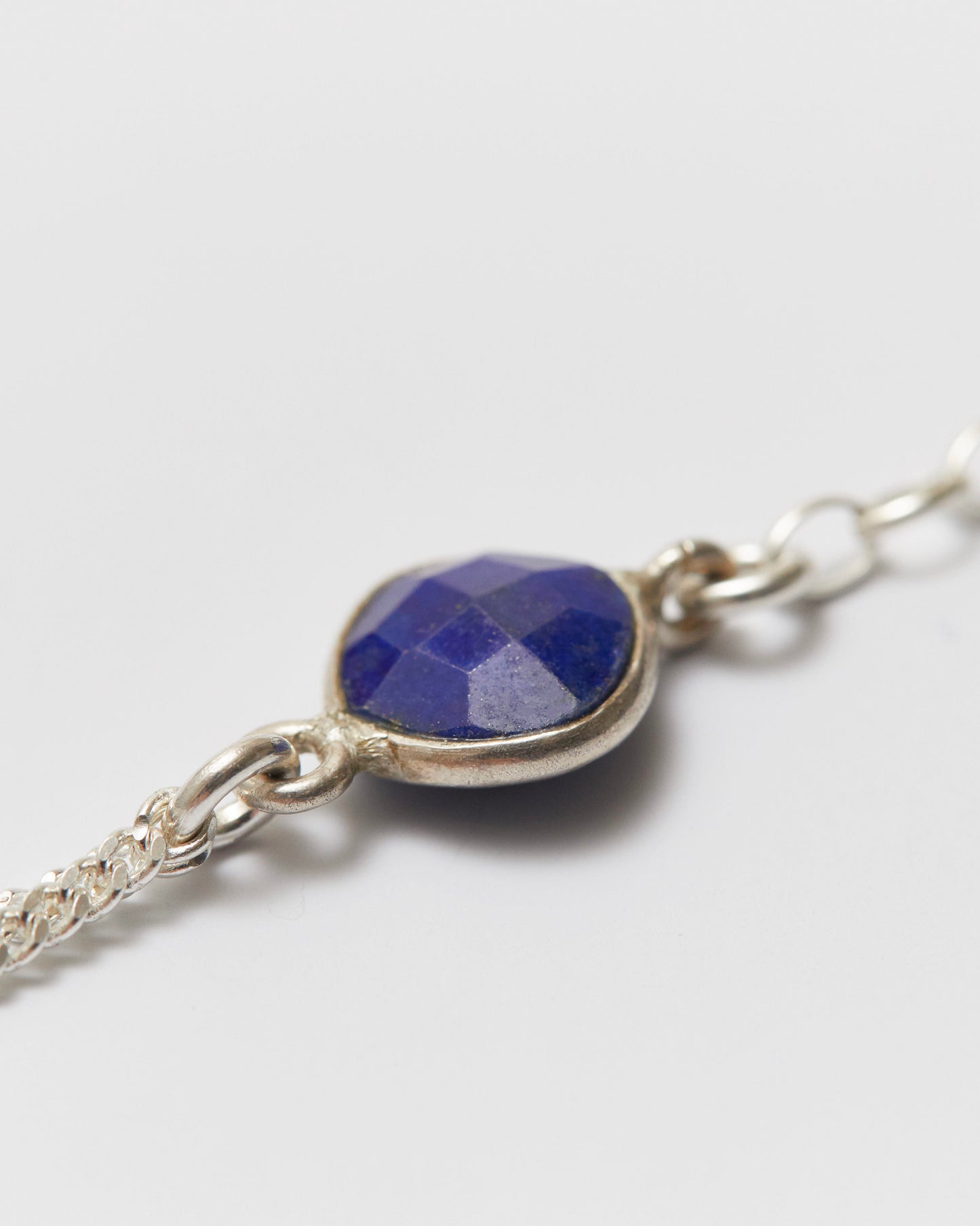 Silver bracelet with a blue gemstone on a light gray background