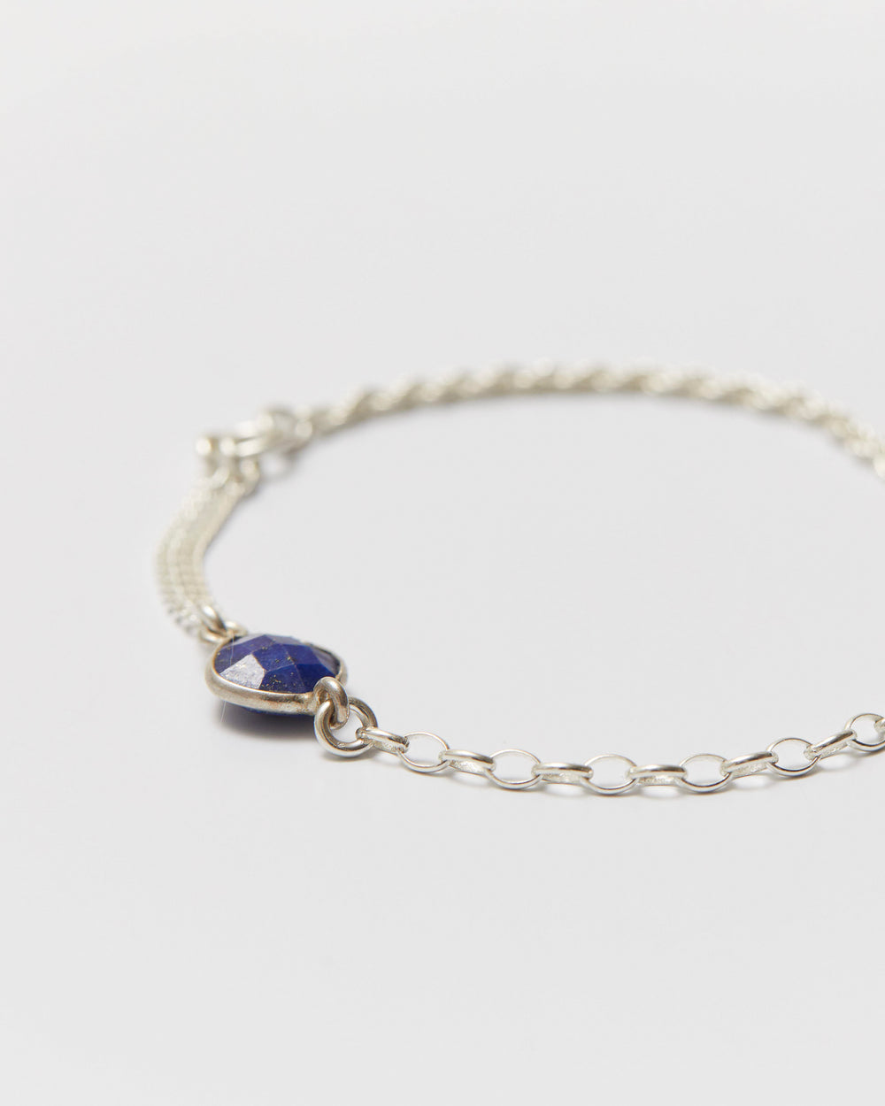 Silver bracelet with a blue gemstone on a light gray background