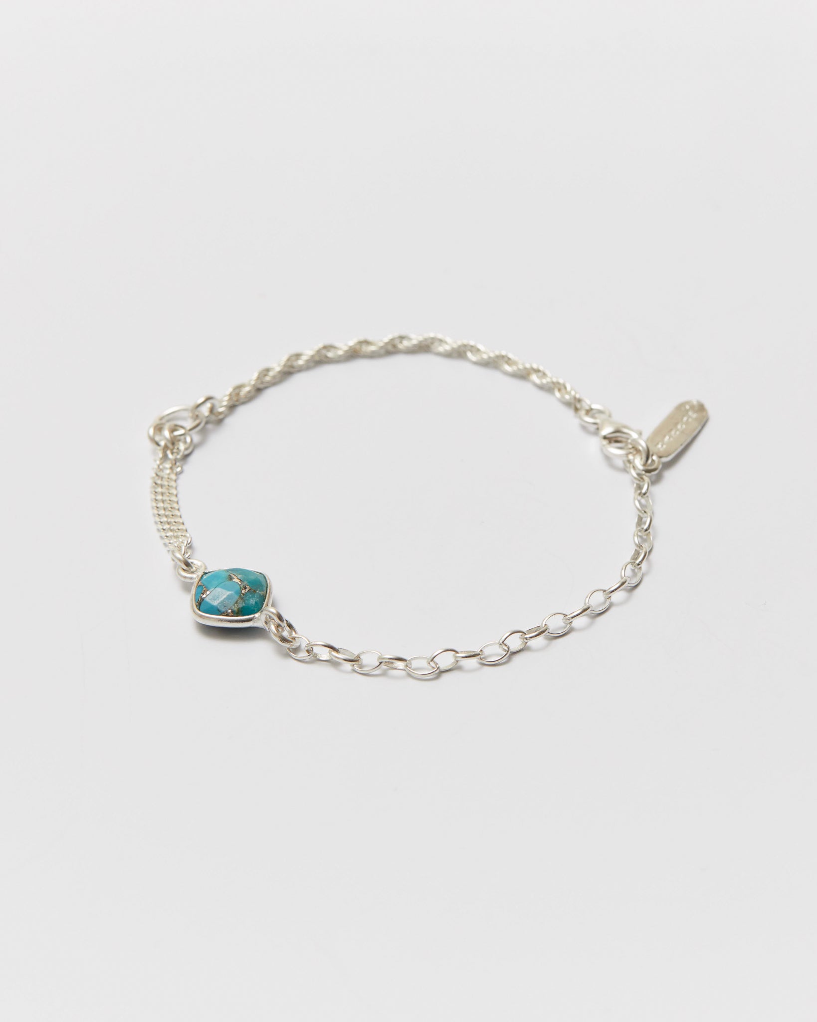 Silver bracelet with a turquoise stone on a light gray background