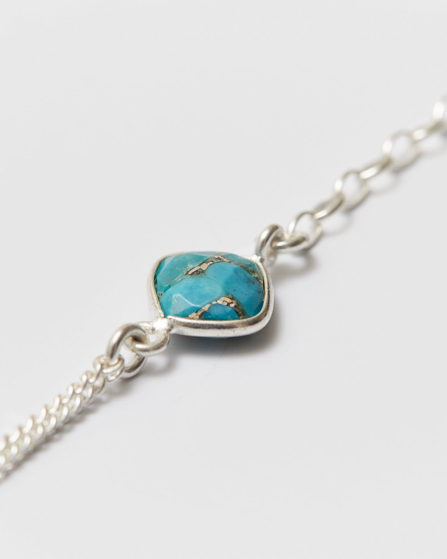 Silver bracelet with a turquoise heart-shaped gemstone on a light gray background