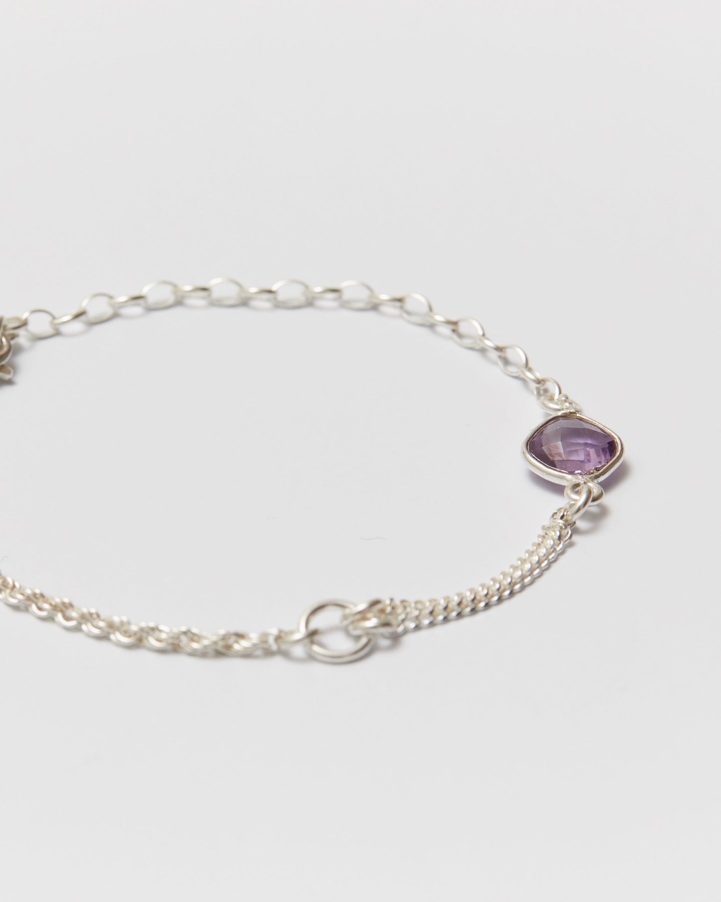 Silver bracelet with a purple gemstone on a light gray background