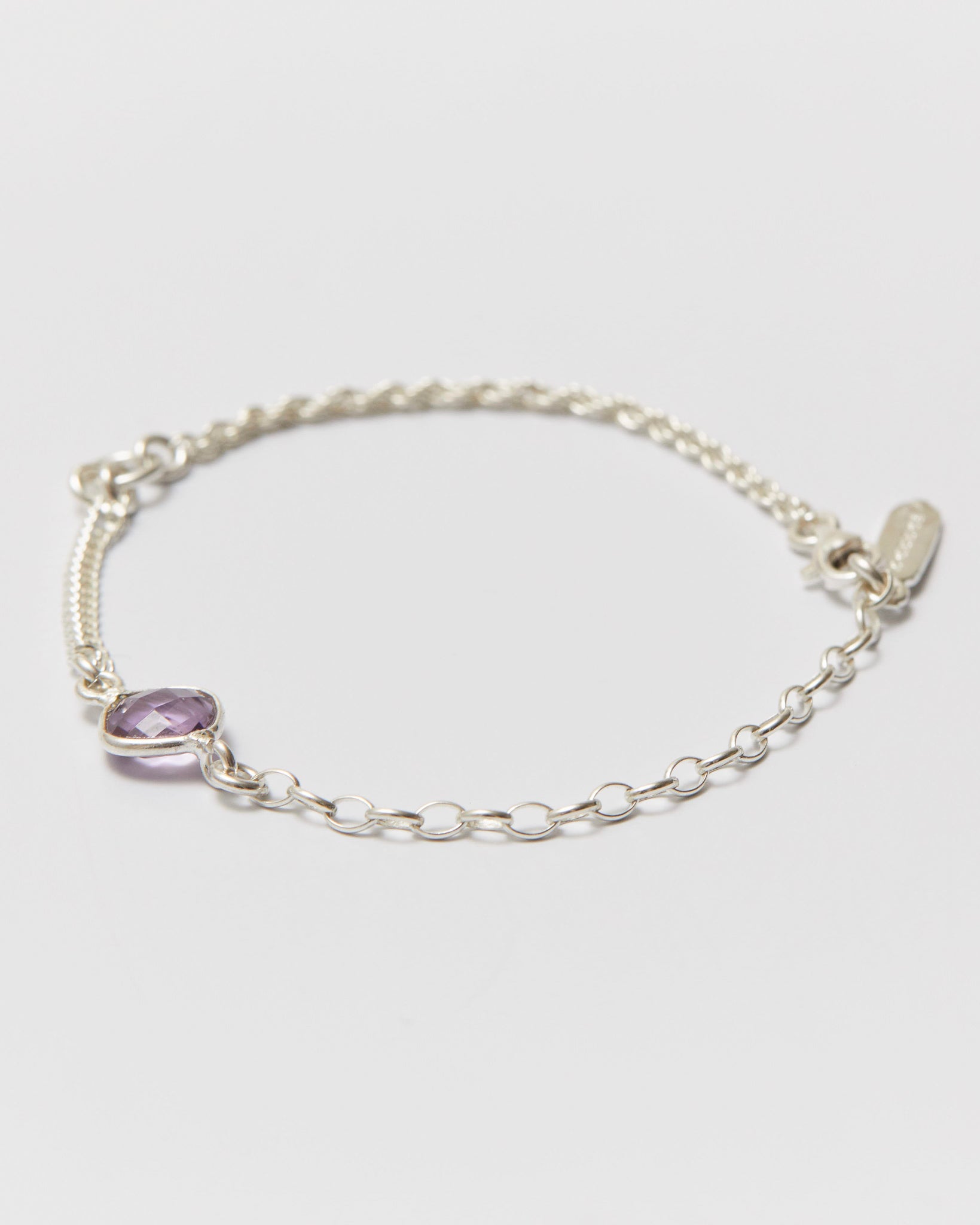 Silver bracelet with a purple gemstone on a light gray background