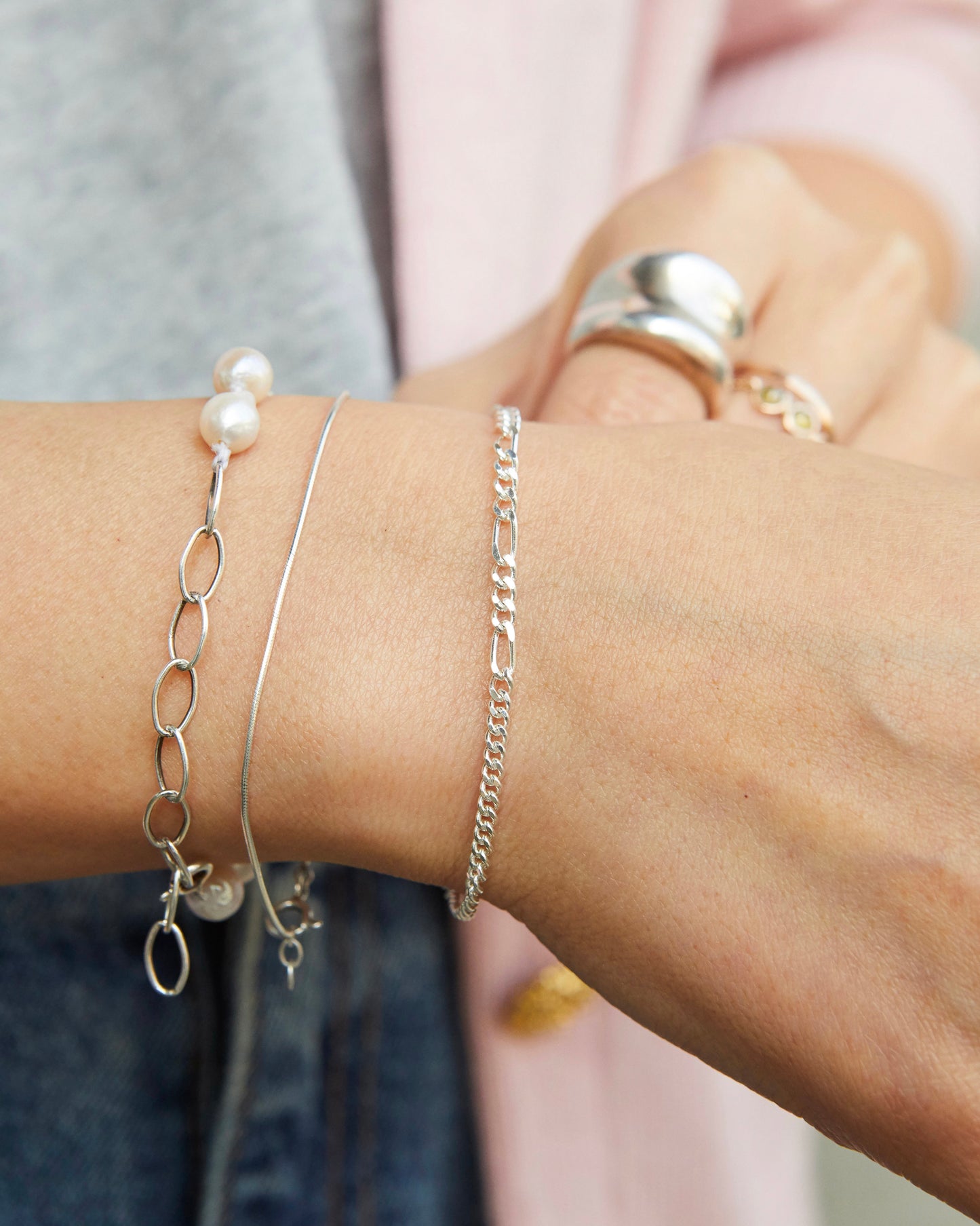 Minimal sterling silver bracelet styled with layered silver jewelry and pearl bracelet for an effortless everyday aesthetic.