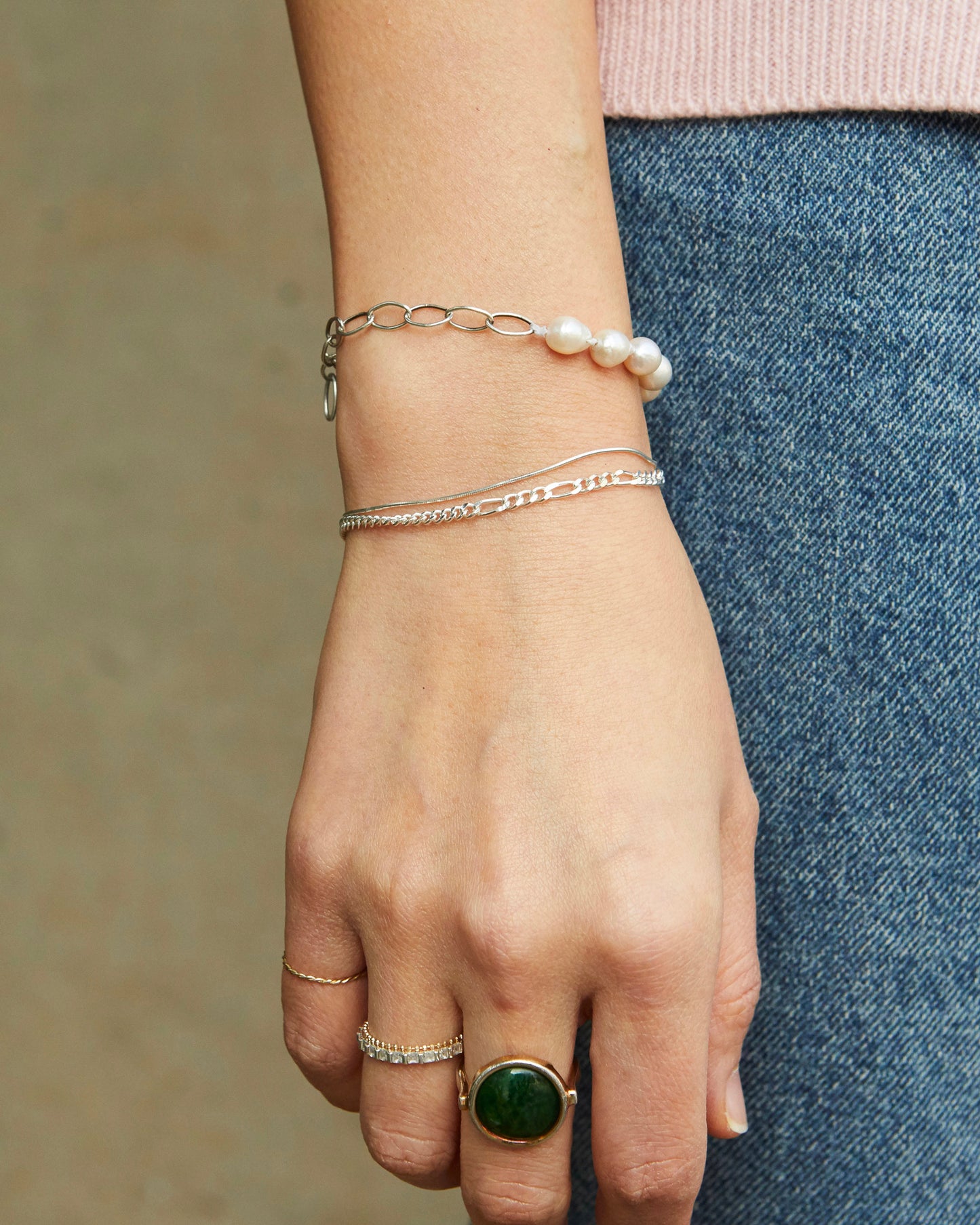 Minimal mixed chain sterling silver bracelet styled casually with rings and layered wrist jewelry for modern everyday wear.