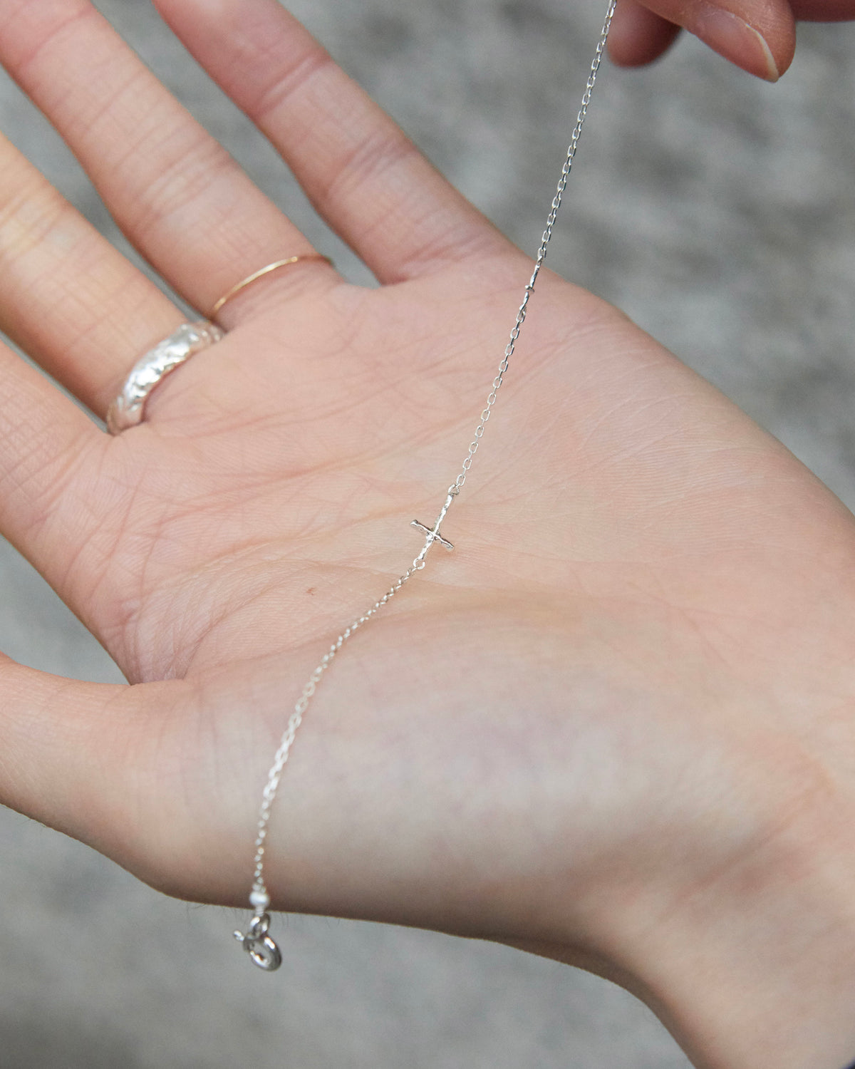 cross axis chain bracelet in silver – draped across an open palm to show the fine chain | HANNA543