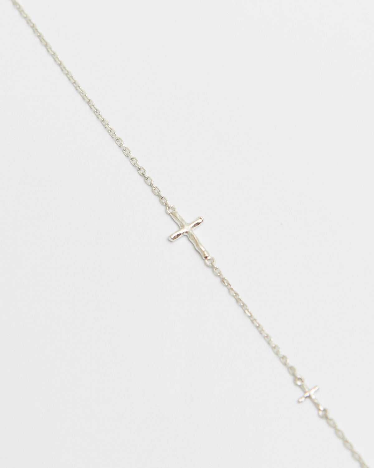 cross axis chain bracelet in silver – close-up of the small cross charm on a fine chain | HANNA543