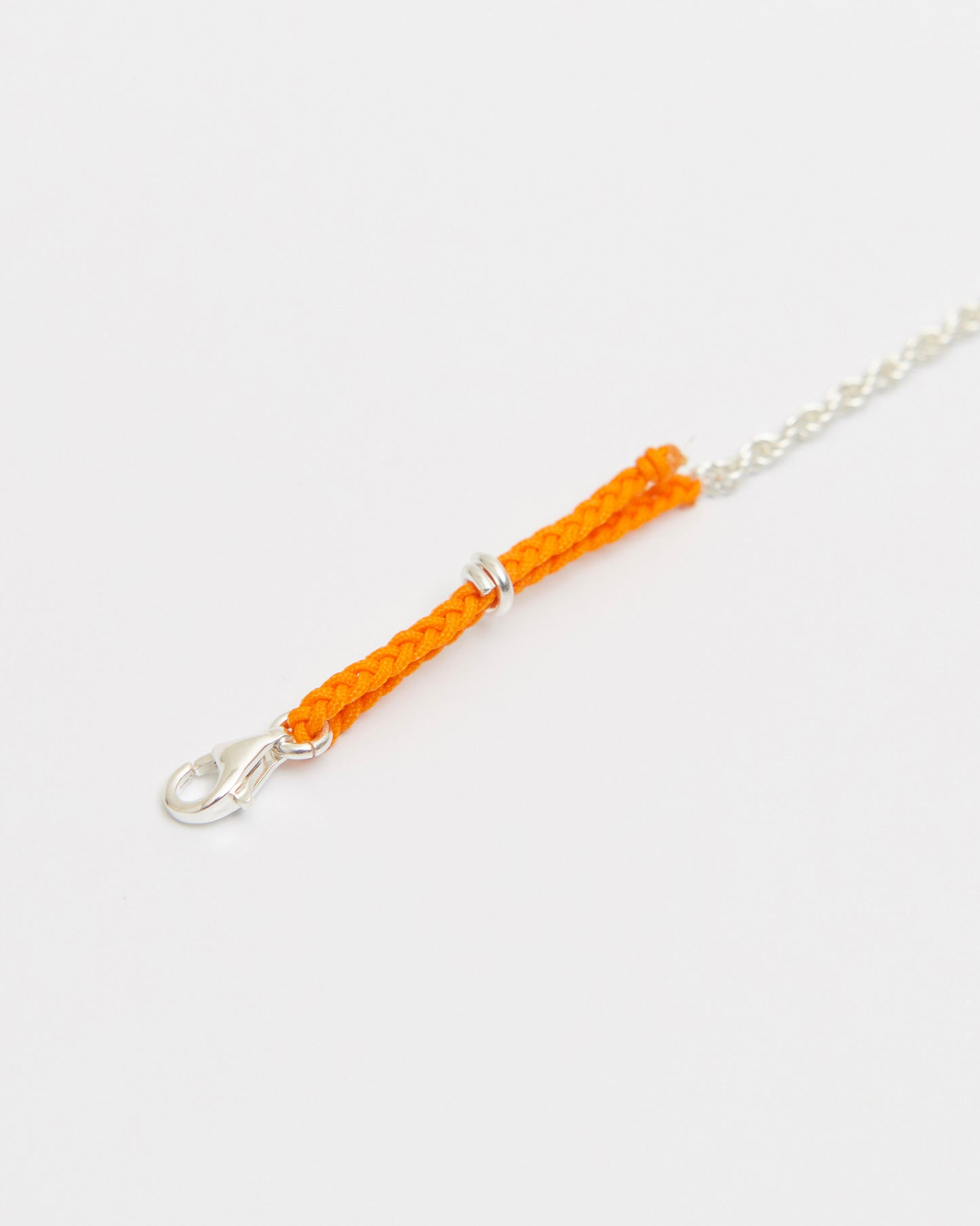 Macro close-up of orange braided cord bracelet with sterling silver hardware and fine chain details.