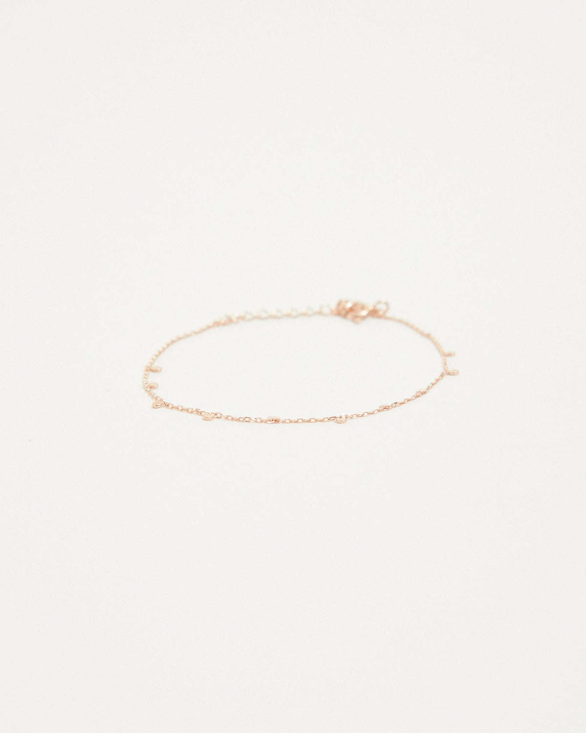 Pink gold plated dot station chain bracelet laid flat on a light background – HANNA543 B96 dew drop garland