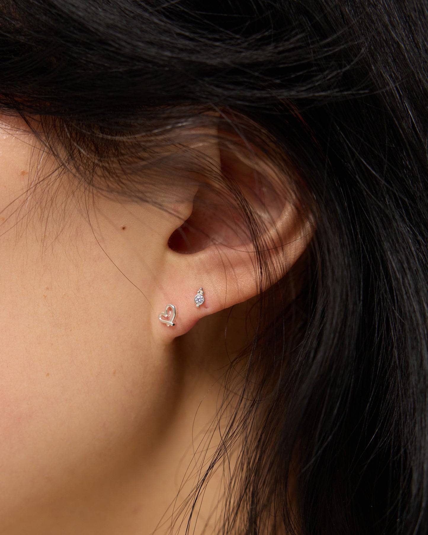 tiny silver stud earring worn close to skin, lightweight and comfortable fit