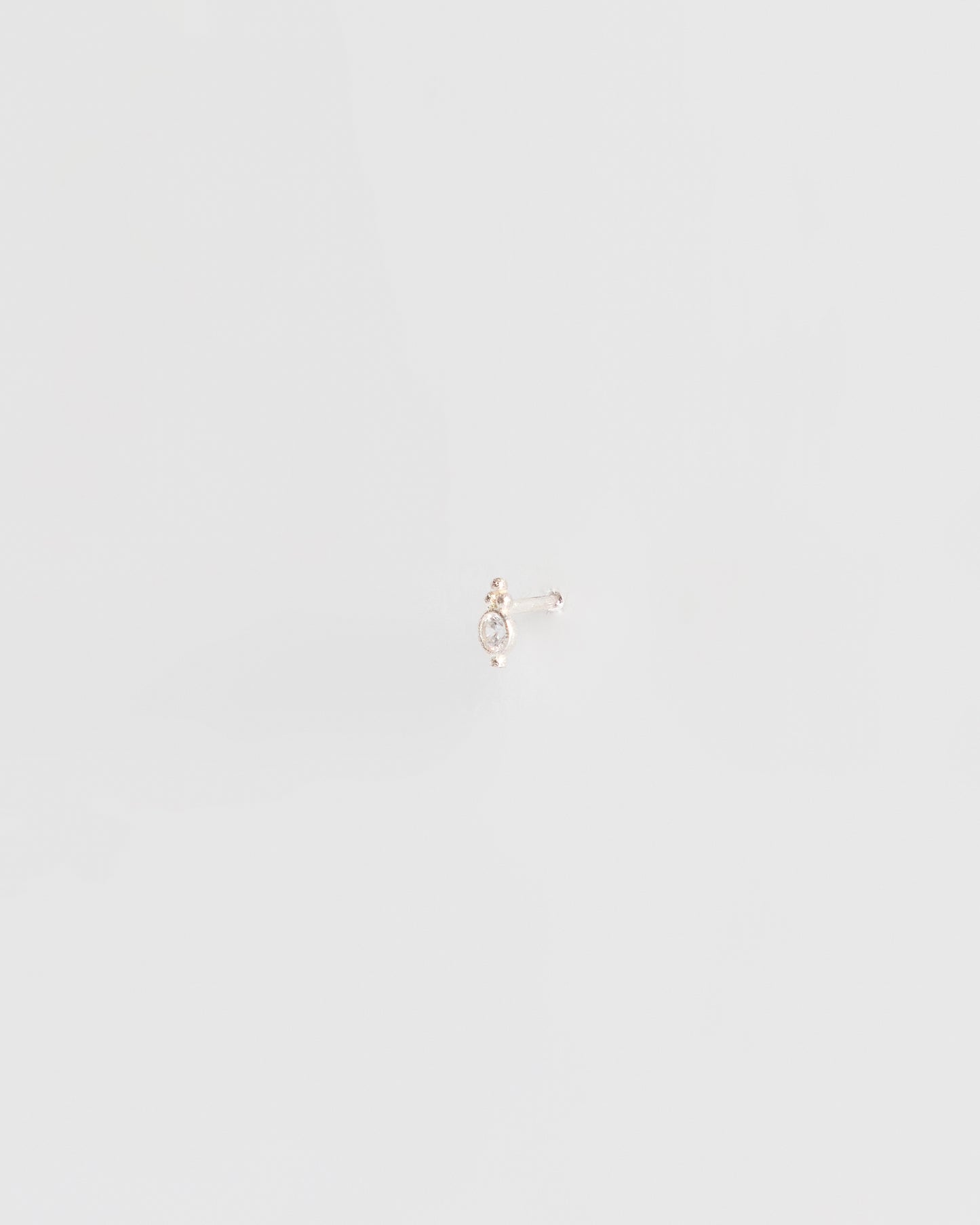 delicate silver stud earring worn on ear, minimal editorial jewelry styling