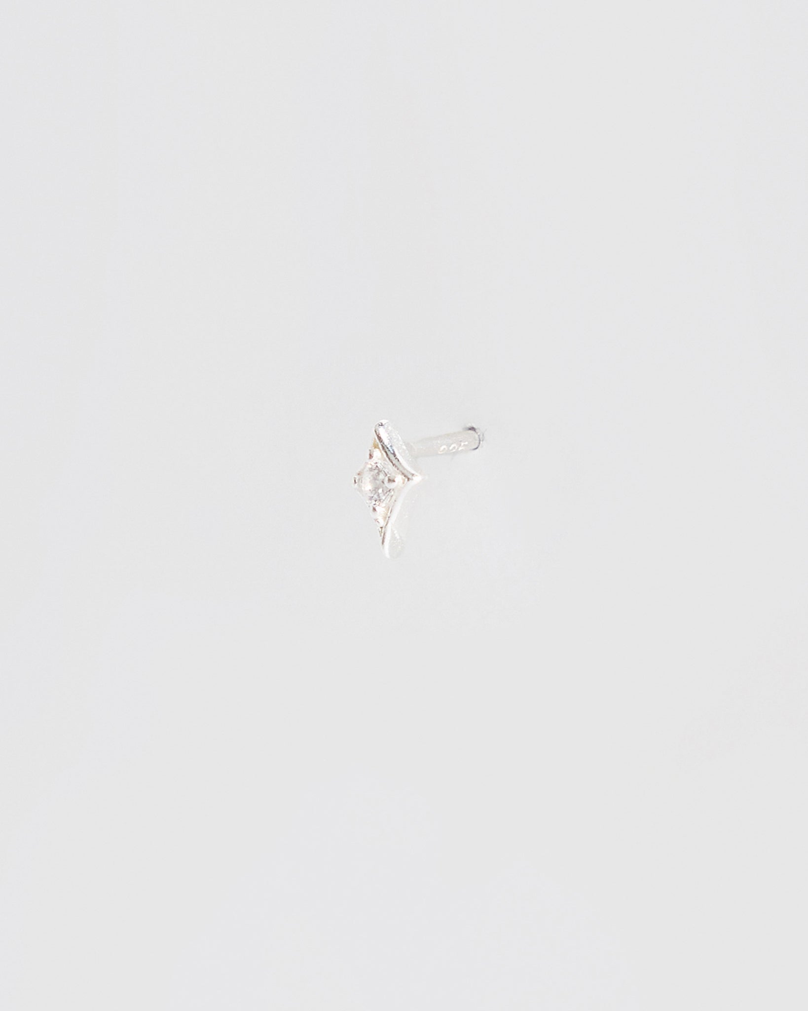 Silver earring on a light gray background