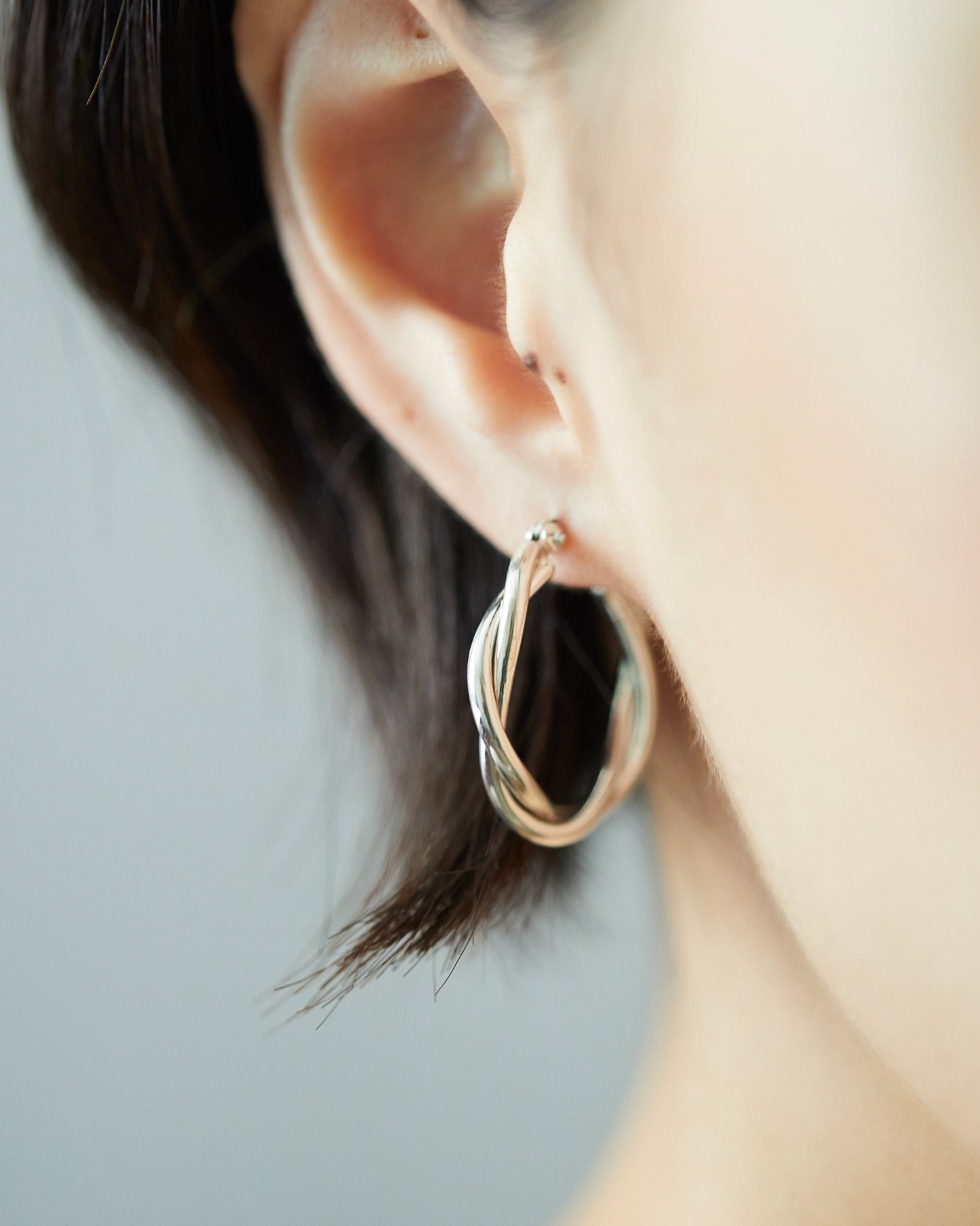 Styling of HANNA543 E324 twisted silver hoop earrings on ear. Daily minimalist jewelry look inspired by BTS Jimin