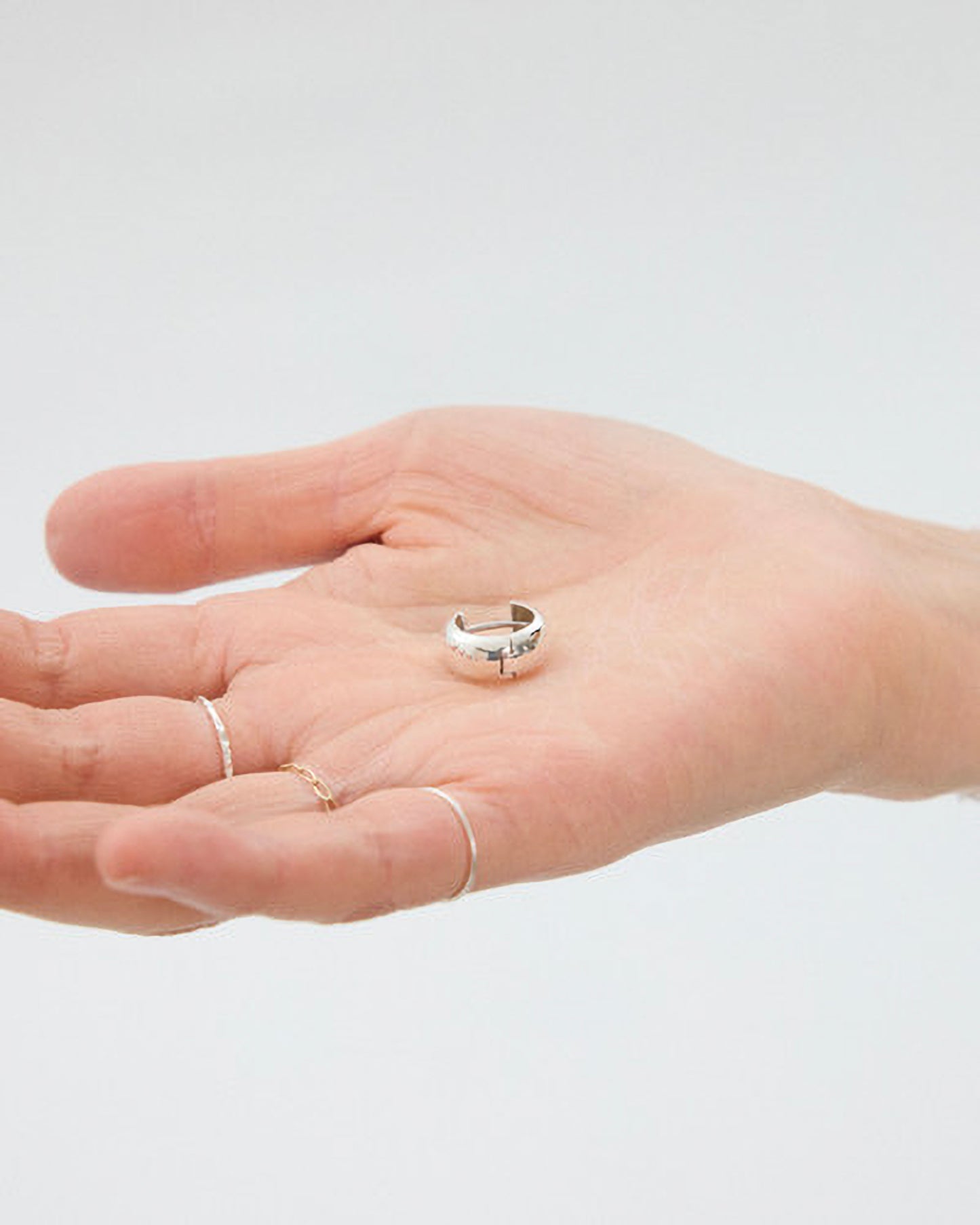 Hand wearing a silver ring on a plain background
