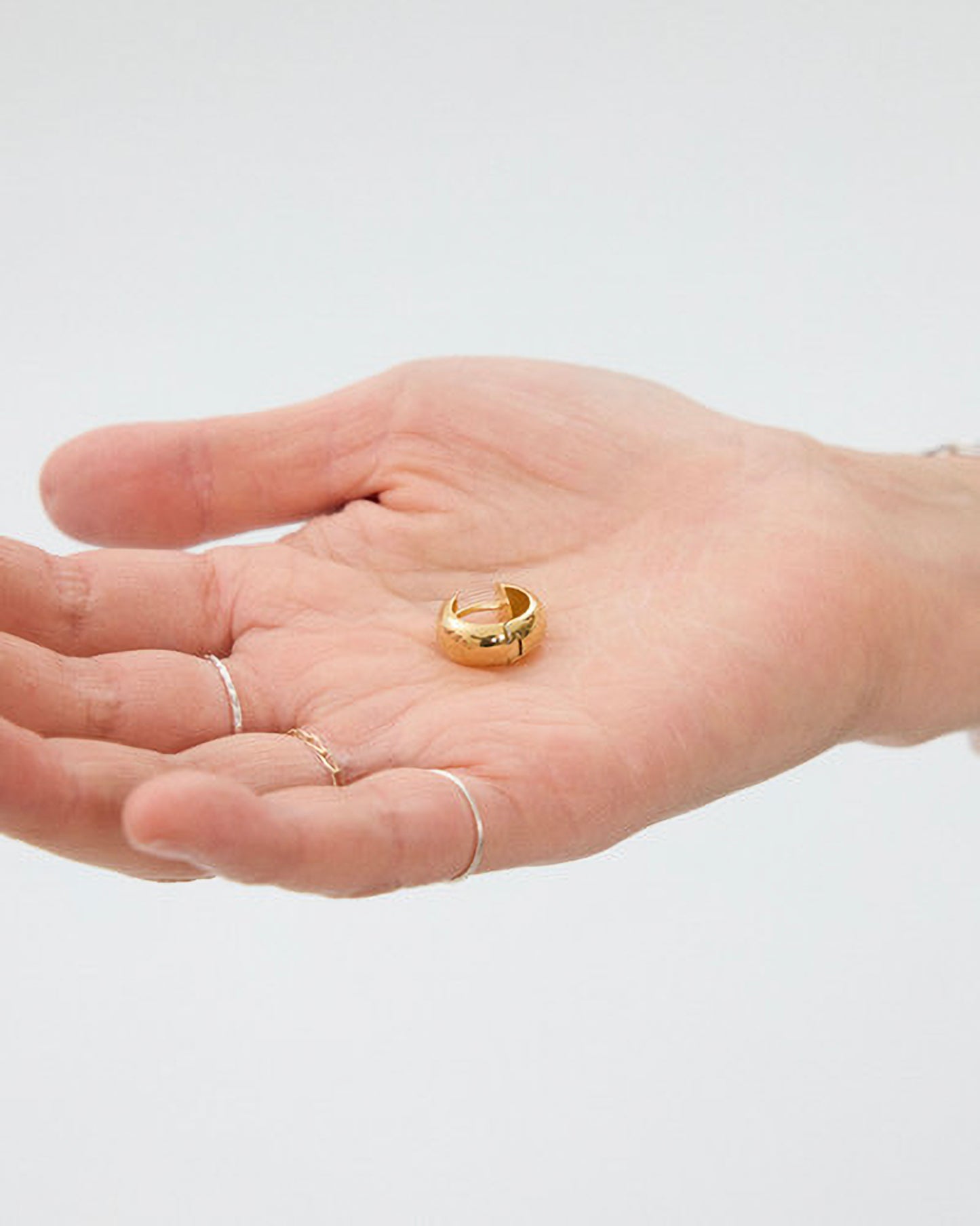 Gold ring on a hand with a plain background