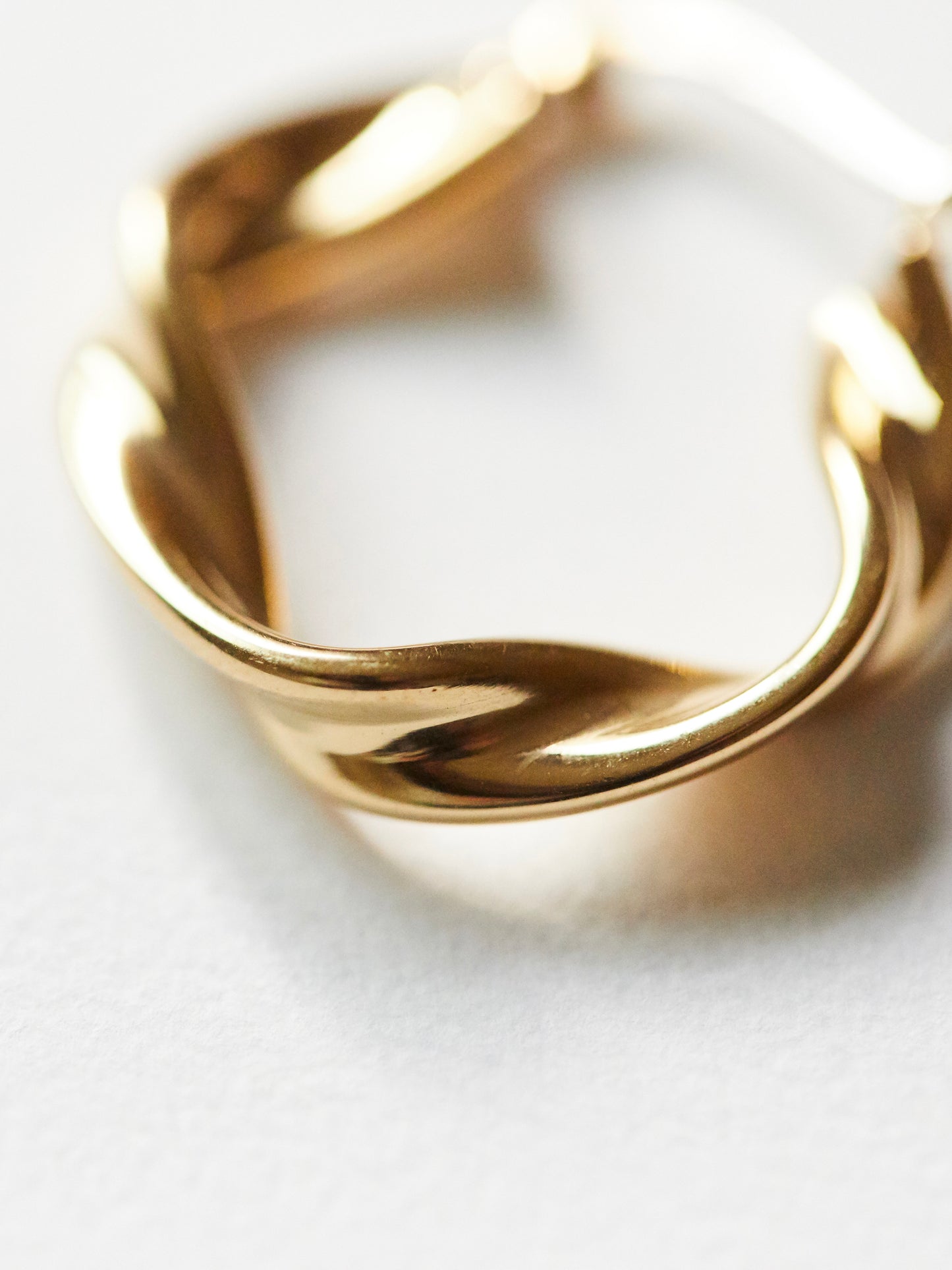 Gold ring with a wavy design on a light background